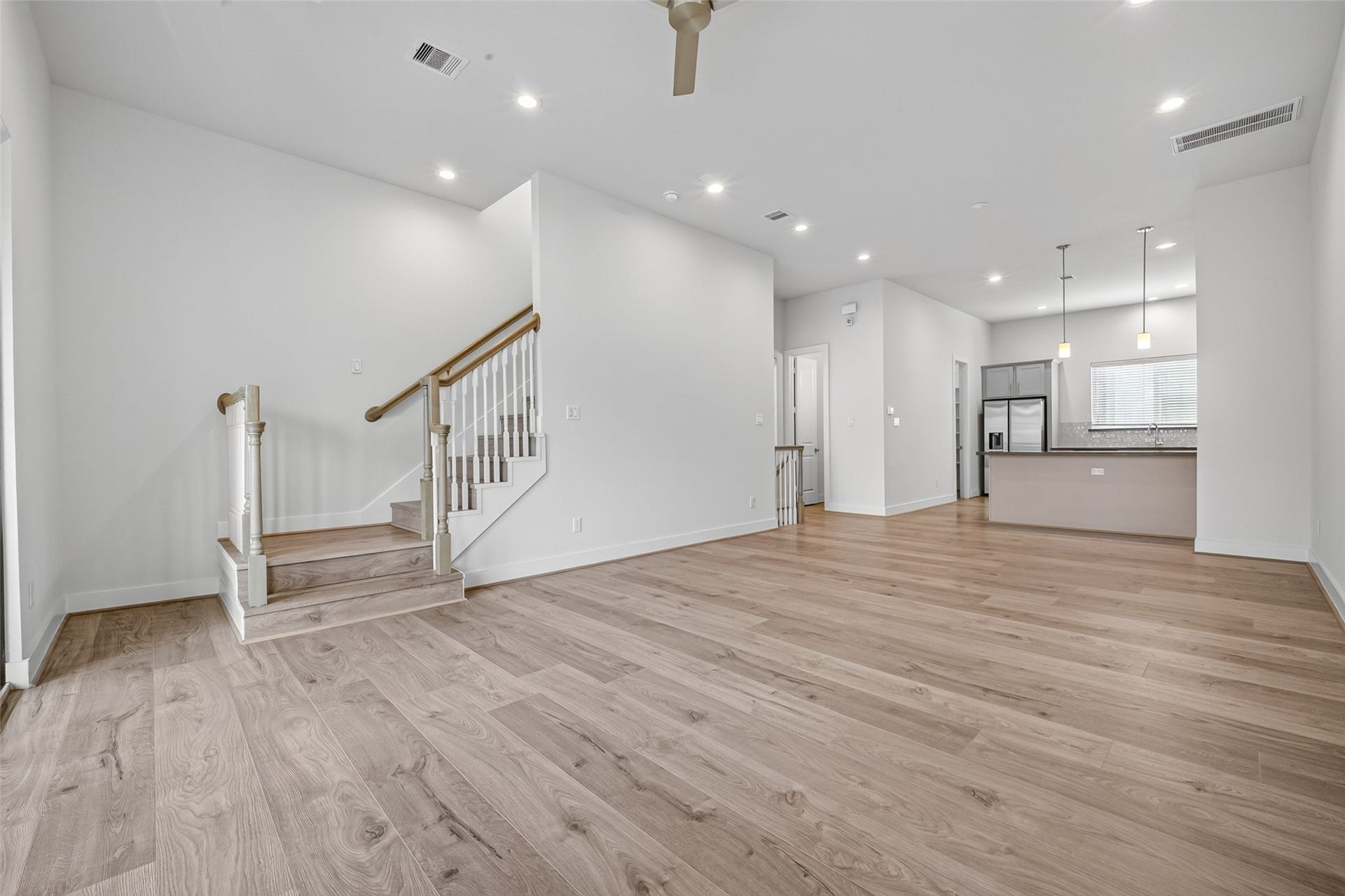Spacious open-concept living area with elegant  LVP floors, leading to a modern kitchen with sleek stainless steel appliances.