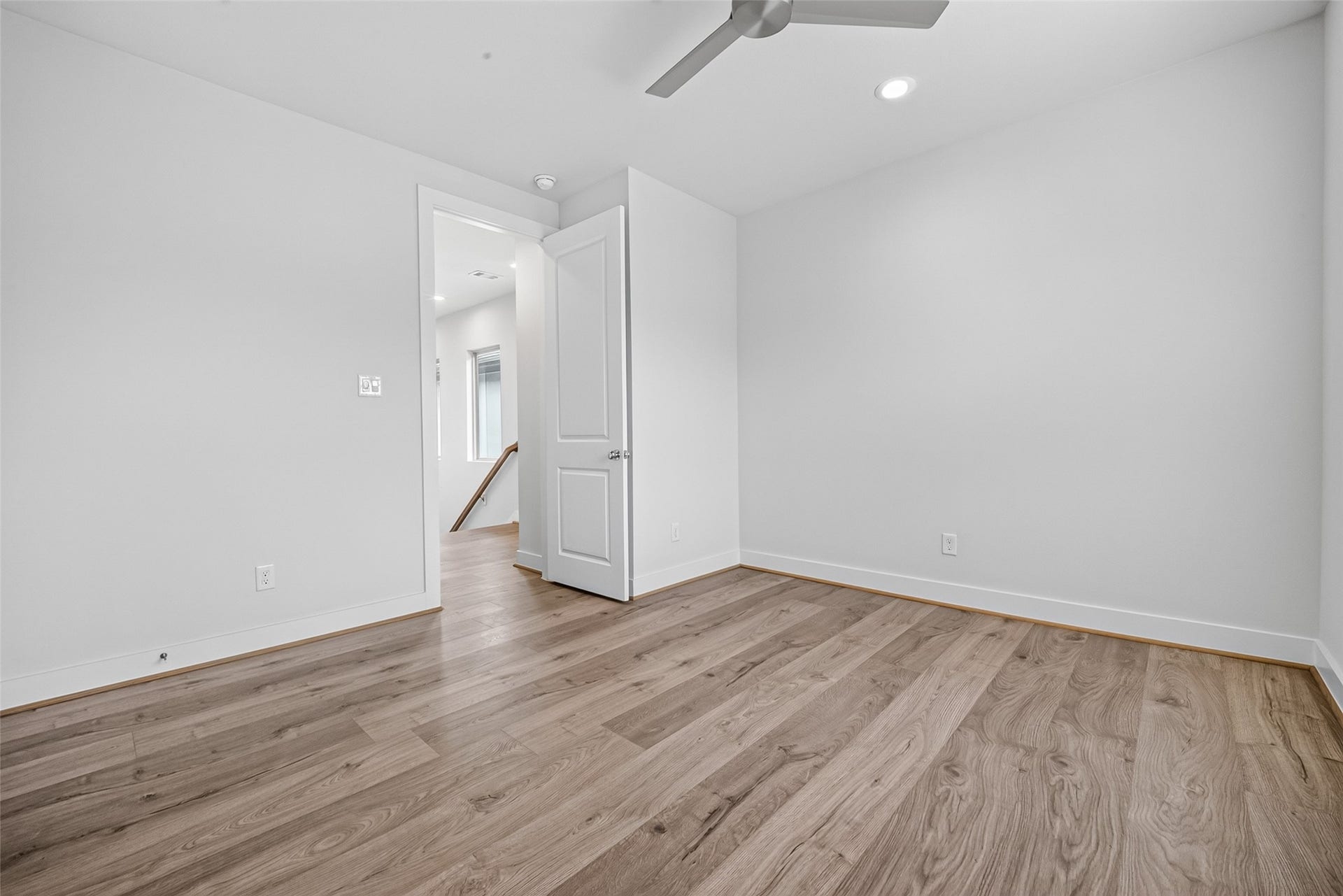 Bright and airy room featuring sleek Swiss flooring, a modern ceiling fan, and recessed lighting, perfect for a cozy bedroom or home office space.