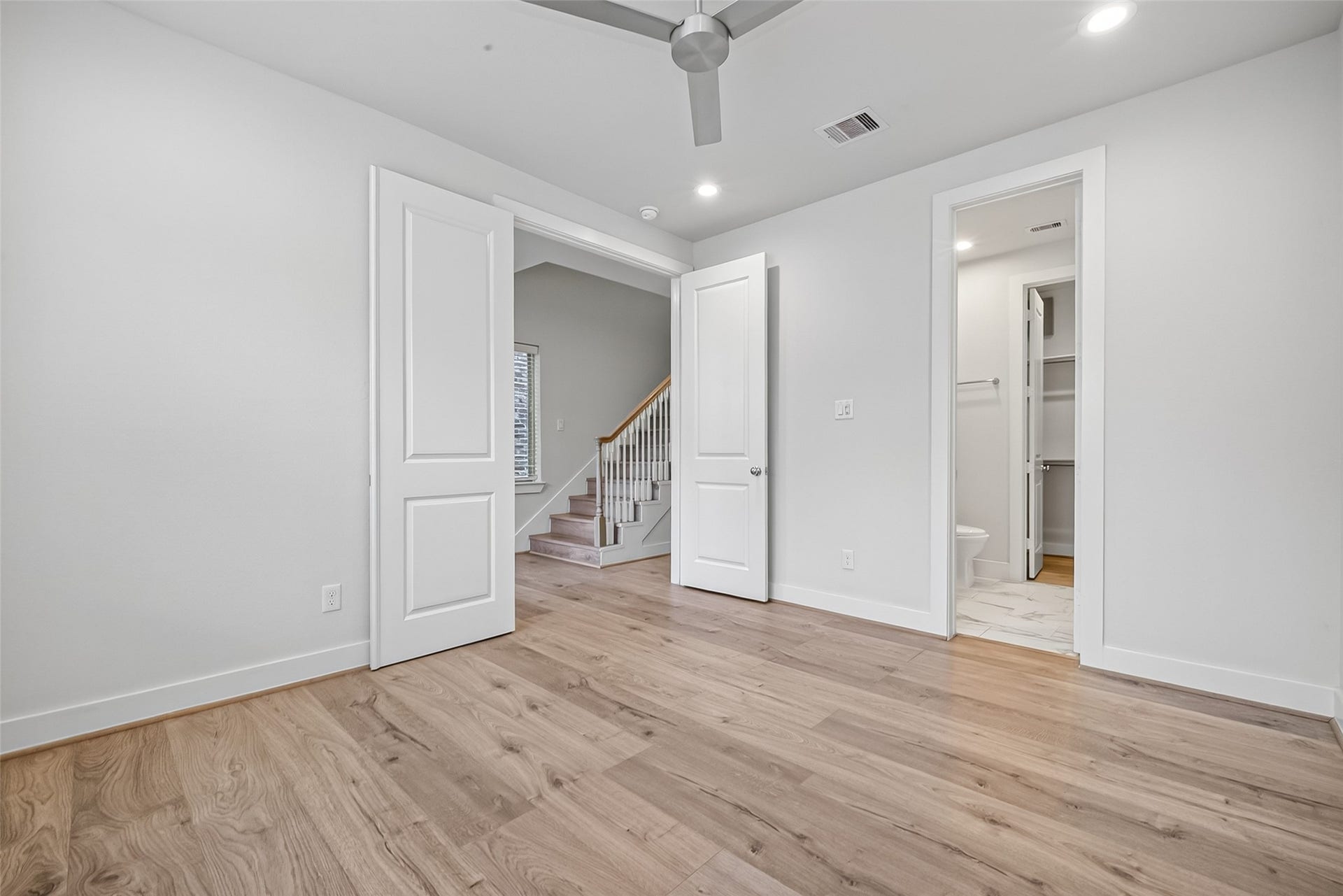 Spacious room featuring elegant Swiss wood like flooring, a sleek ceiling fan, and access to an en-suite bathroom with modern fixtures.  Great Office Space away from all the hustle and bustle