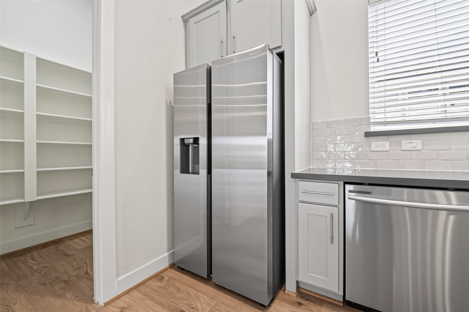 Modern kitchen features sleek stainless steel appliances, ample cabinetry, and a convenient walk-in pantry for optimal storage.
