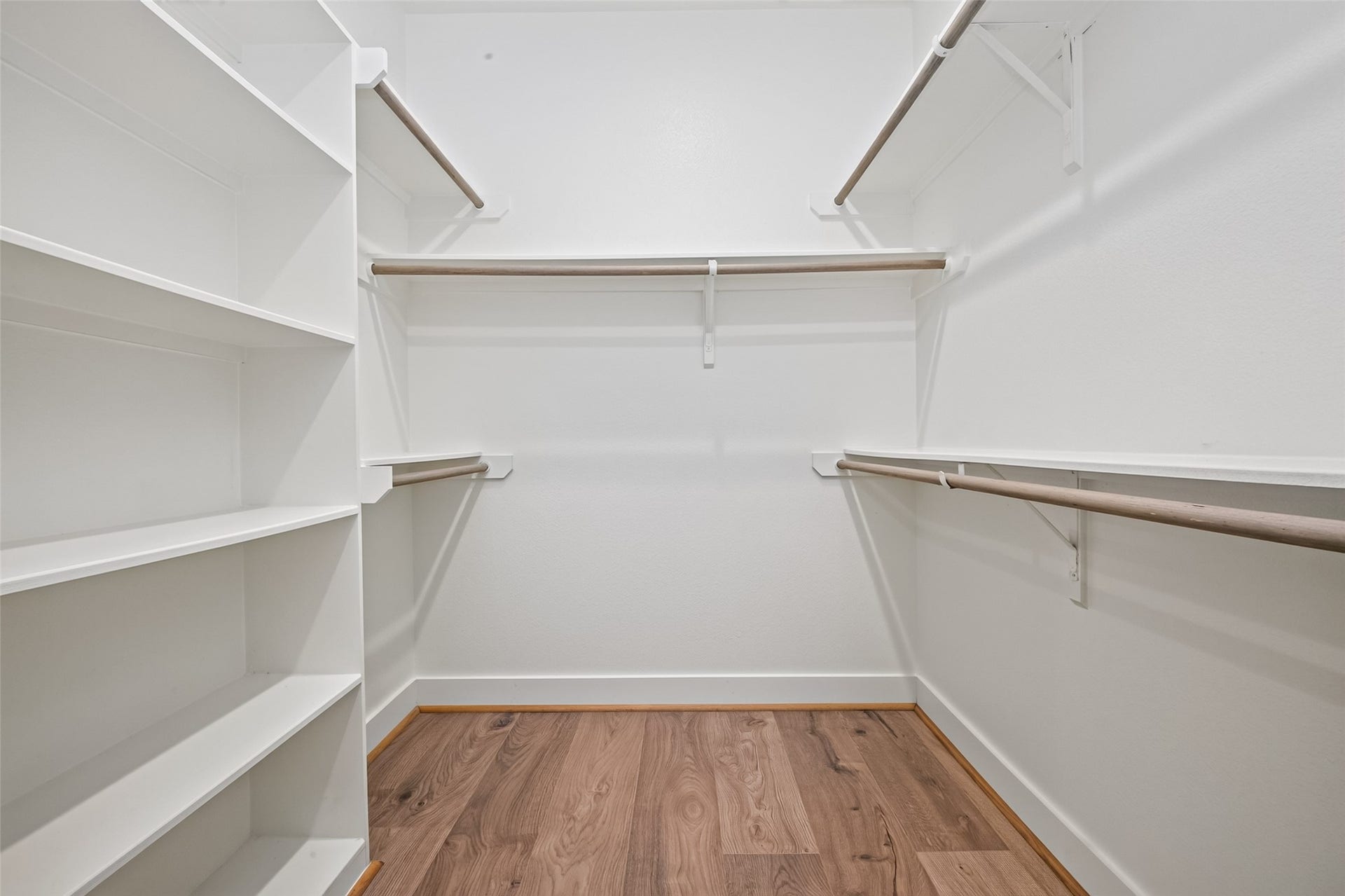 Spacious walk-in closet featuring ample shelving and multiple hanging rods, perfect for organized storage.