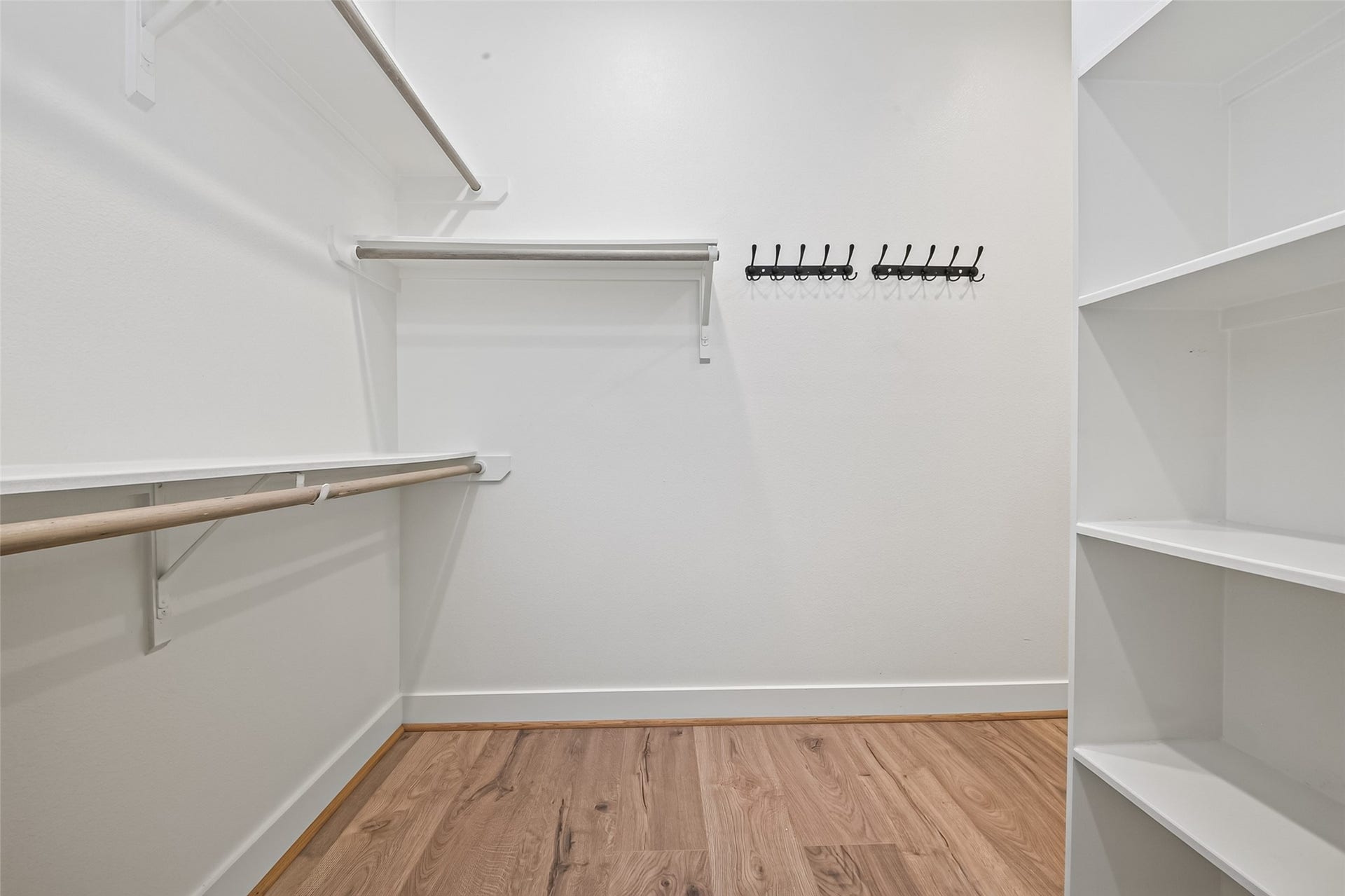 Spacious walk-in closet with ample shelving, hanging rods, and hooks, perfect for organized storage.