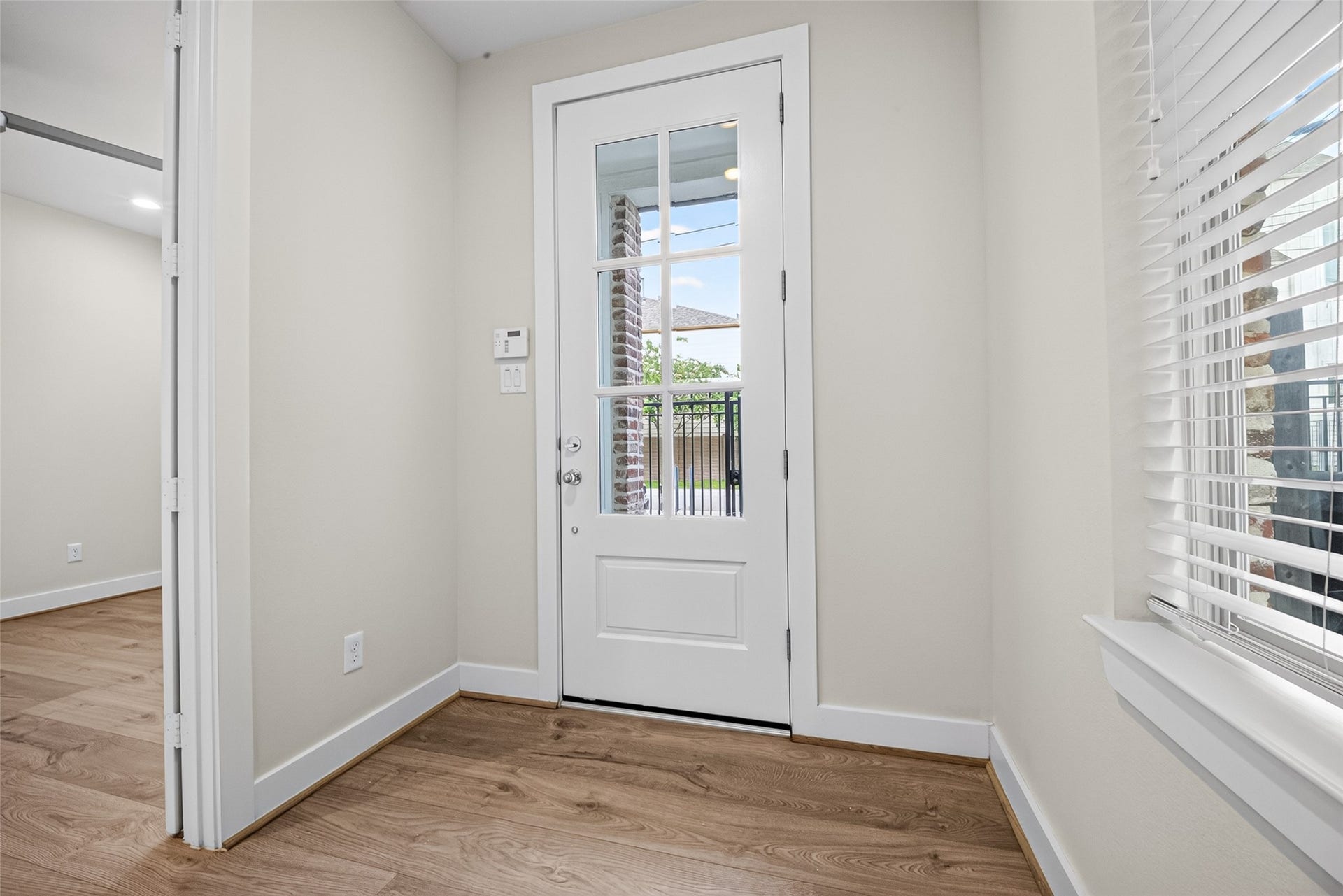 Bright entryway features a glass-paneled door and sleek Swiss flooring, leading into a welcoming space filled with natural light.