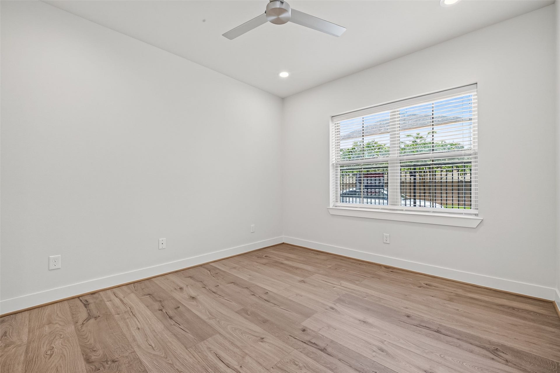 Bright and airy 3rd floor secondary bedroom featuring sleek Swiss floors, a modern ceiling fan, and a large window allowing plenty of natural light.