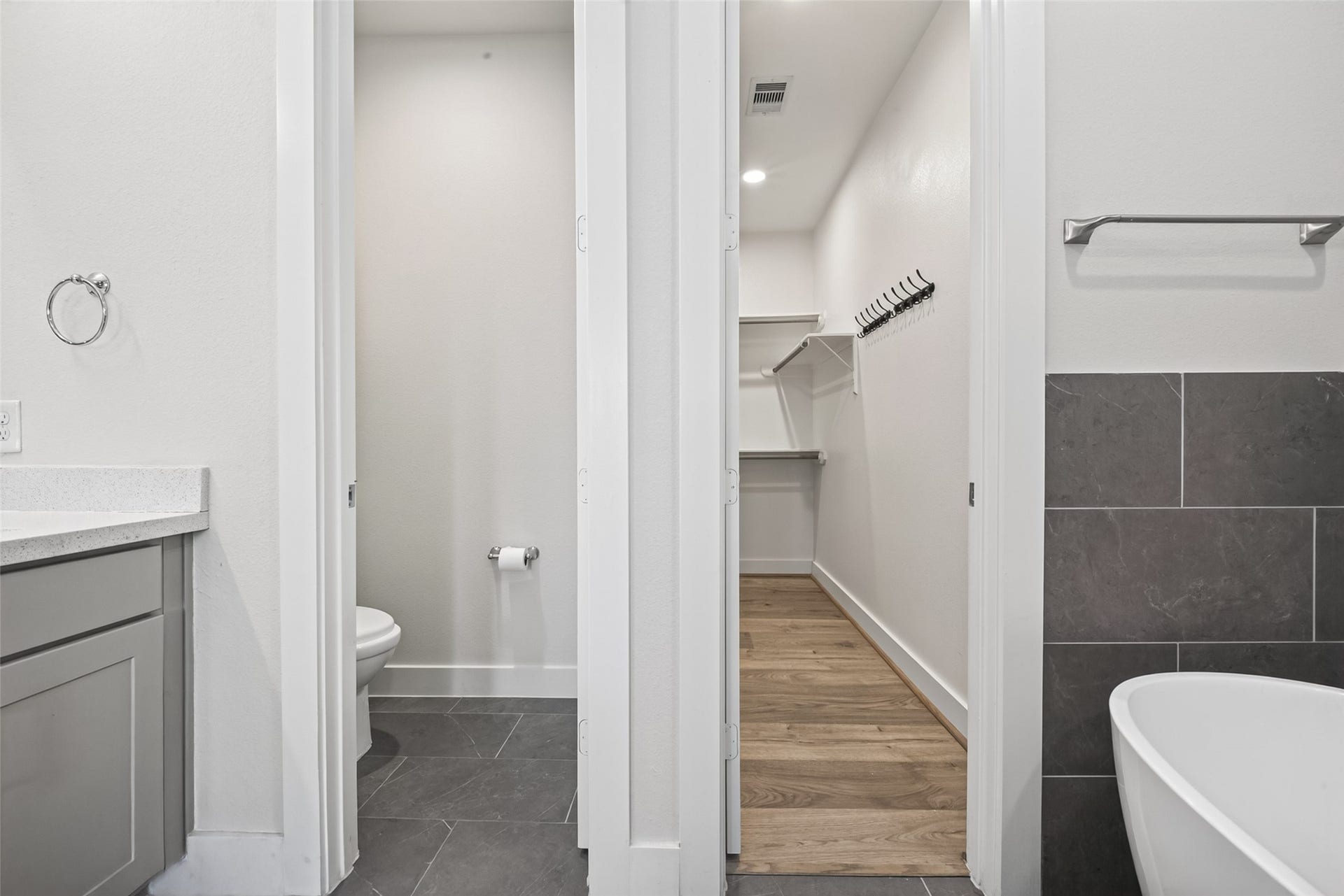 En-suite bathroom features a sleek vanity, separate toilet area, and a spacious walk-in closet with ample shelving and hanging space.