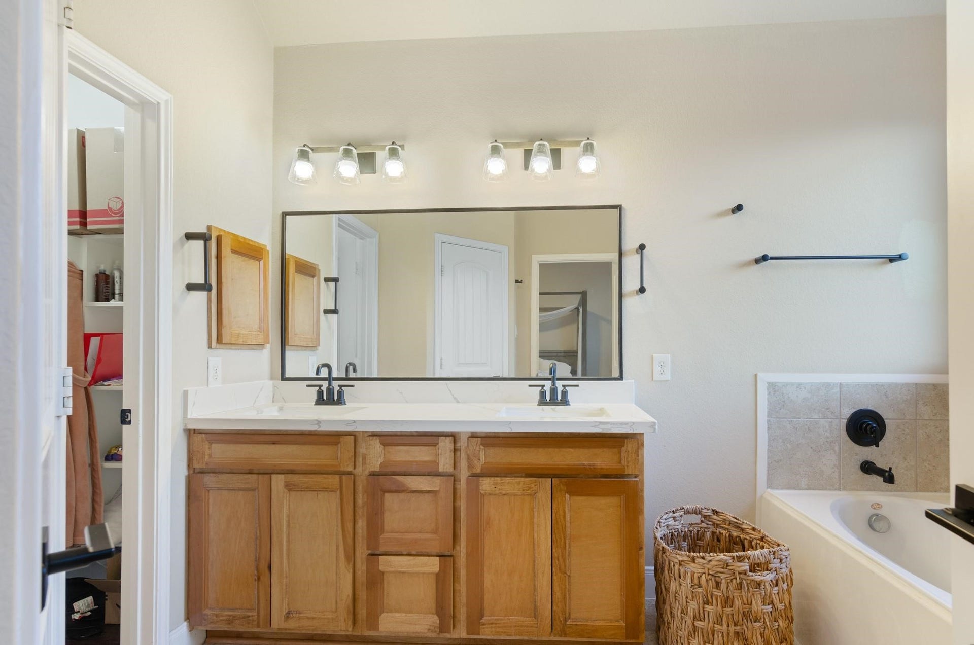 103 W Wading Pond Circle, Tomball, TX 77375 Directly adjoining the primary bedroom, the ensuite bathroom delivers spa-like convenience. It features an extended dual-sink vanity with warm natural wood cabinetry and contemporary matte black fixtures, an oversized vanity mirror, a walk-in wardrobe, and a deep soaking garden tub with decorative tile surroundideal for unwinding after a busy day.