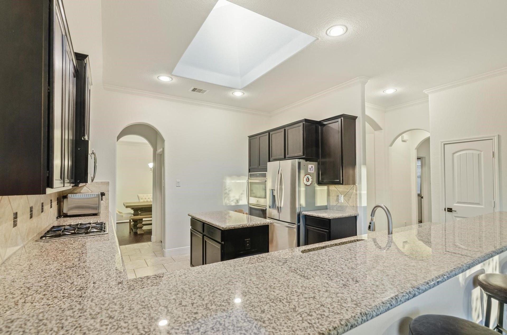 103 W Wading Pond Circle, Tomball, TX 77375 Rich espresso cabinetry contrasts with expansive granite countertops, complemented by stainless-steel appliances, a gas cooktop, built-in microwave, and a convenient center preparation island.