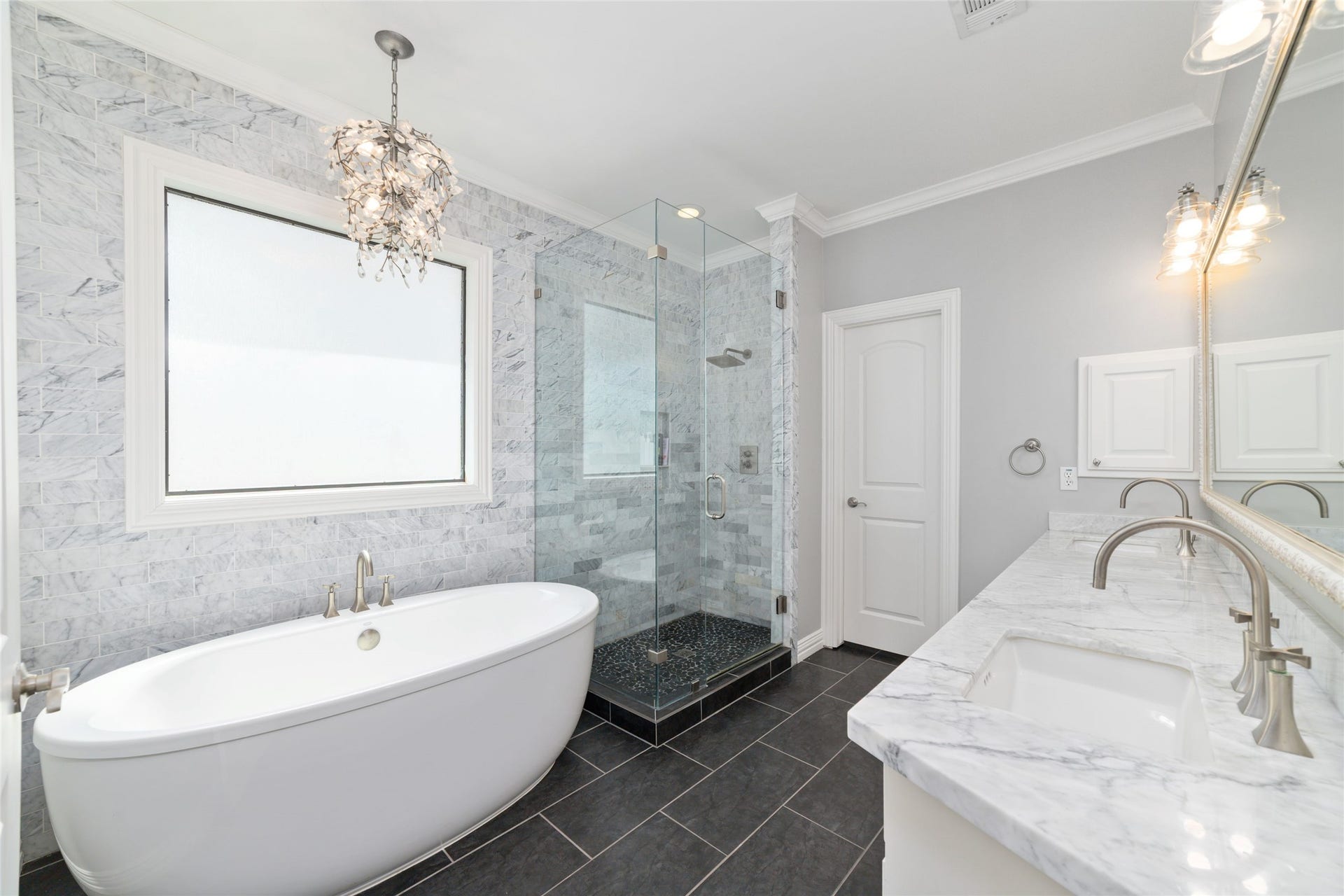 Spa-inspired primary bath featuring a freestanding soaking tub, frameless glass shower, and dual vanities.