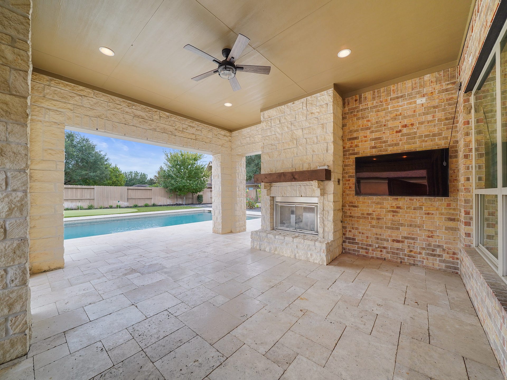 27710 Guthrie Ridge Lane, Katy, TX 77494 Out back, the covered patio unfolds as an open-air living room, complete with a fireplace and a backdrop of poolside views.