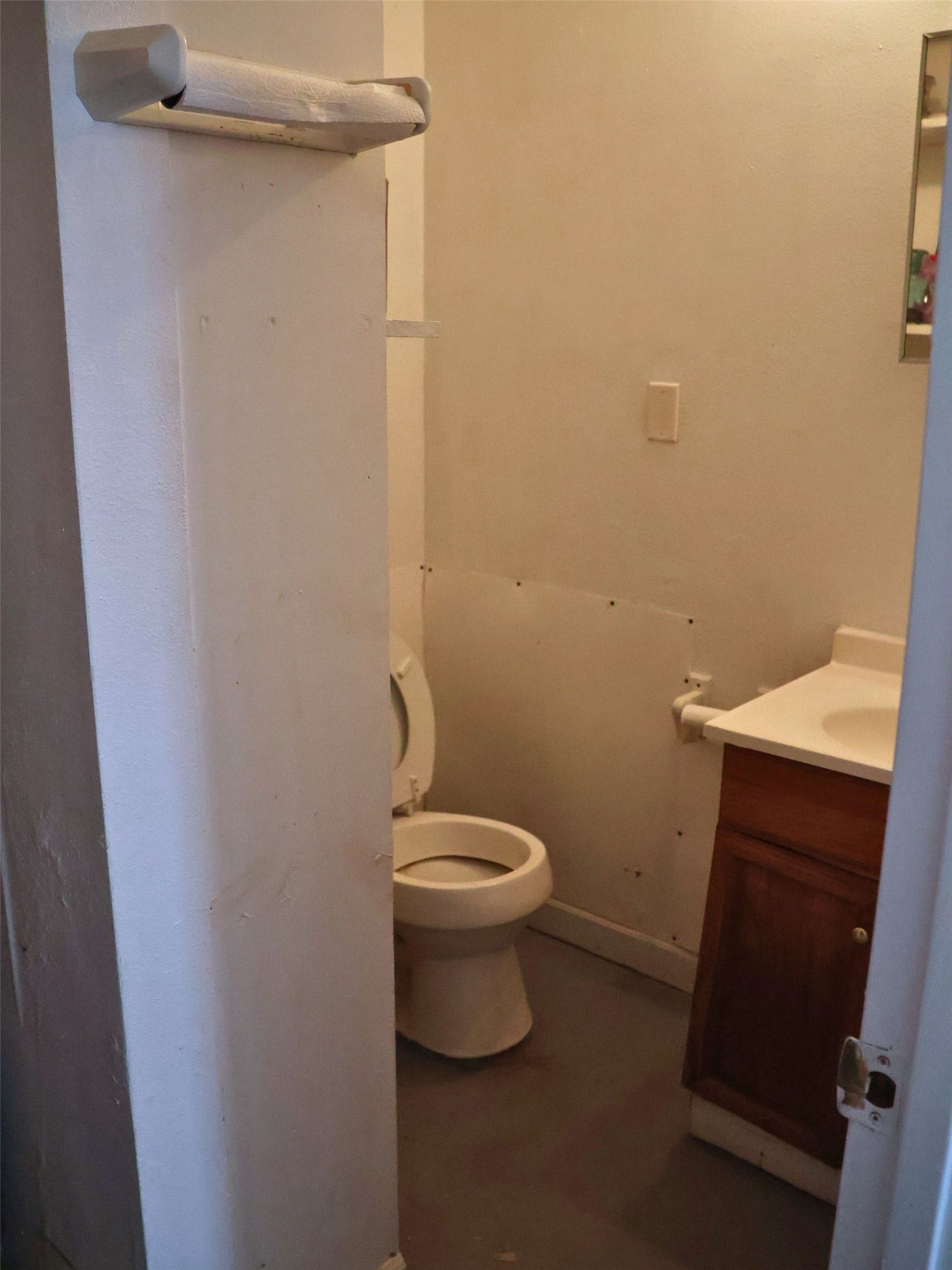 3401 Highway 6, Hitchcock, TX 77563 This photo shows a compact bathroom with a toilet, a small vanity with a sink, and a towel rack. The space appears basic and might benefit from some updates.