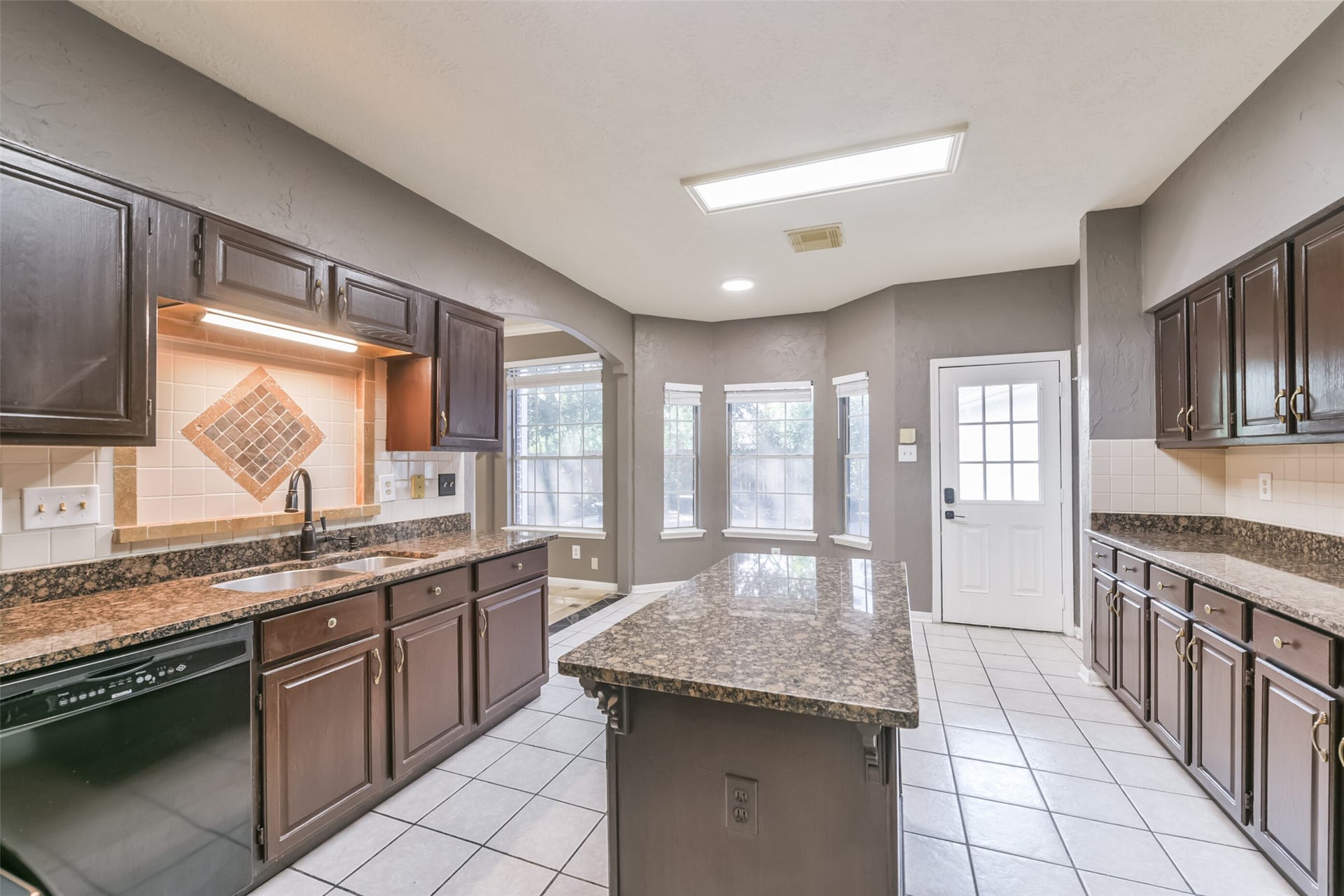 2509 S Mission Circle, Friendswood, TX 77546 Spacious kitchen with elegant dark cabinetry, granite countertops, and ample natural light from large windows, perfect for culinary enthusiasts.