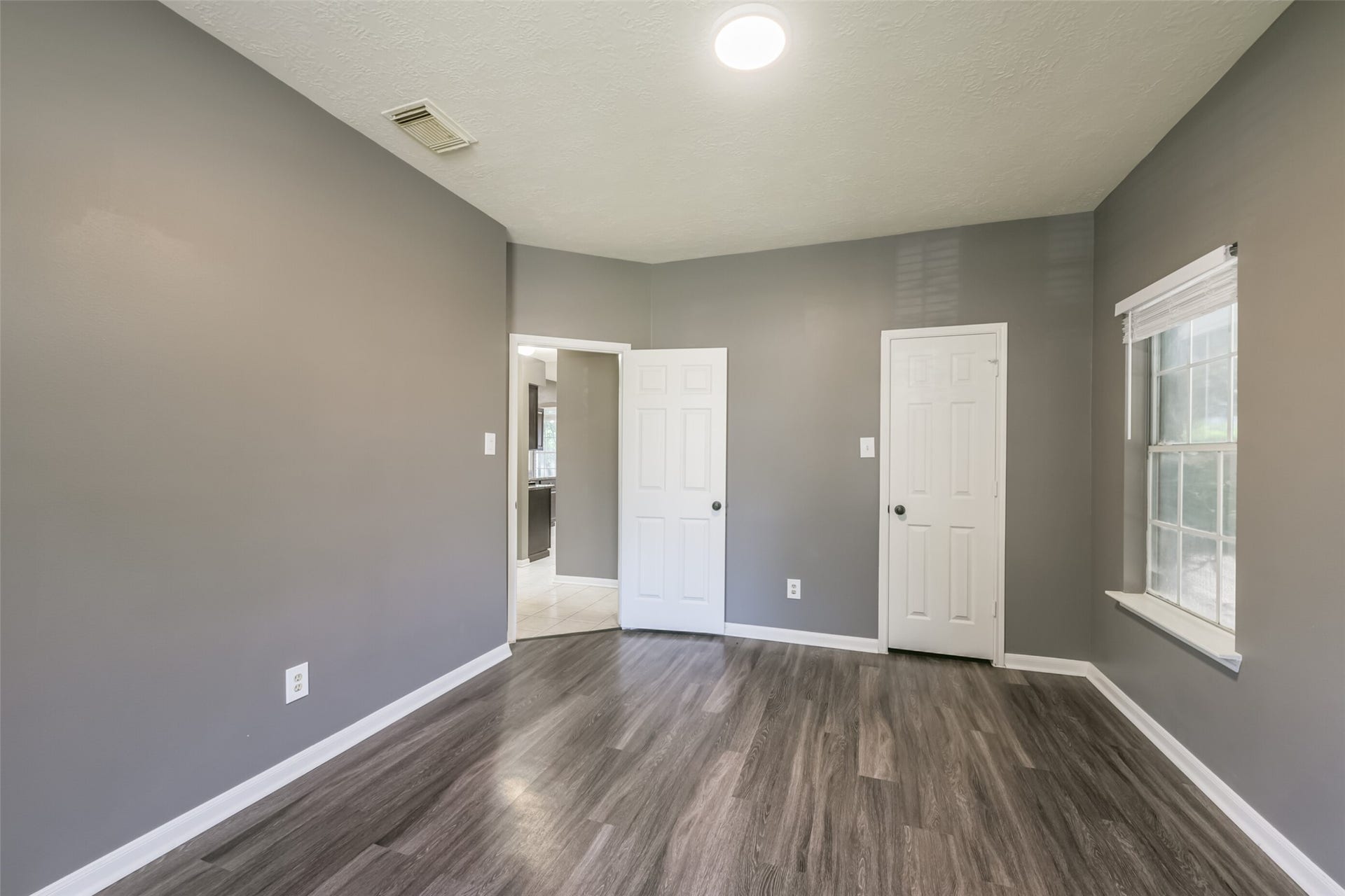 2509 S Mission Circle, Friendswood, TX 77546 Experience comfort and style in this inviting guest room, featuring sleek hardwood floors, soft gray walls, and abundant natural light.