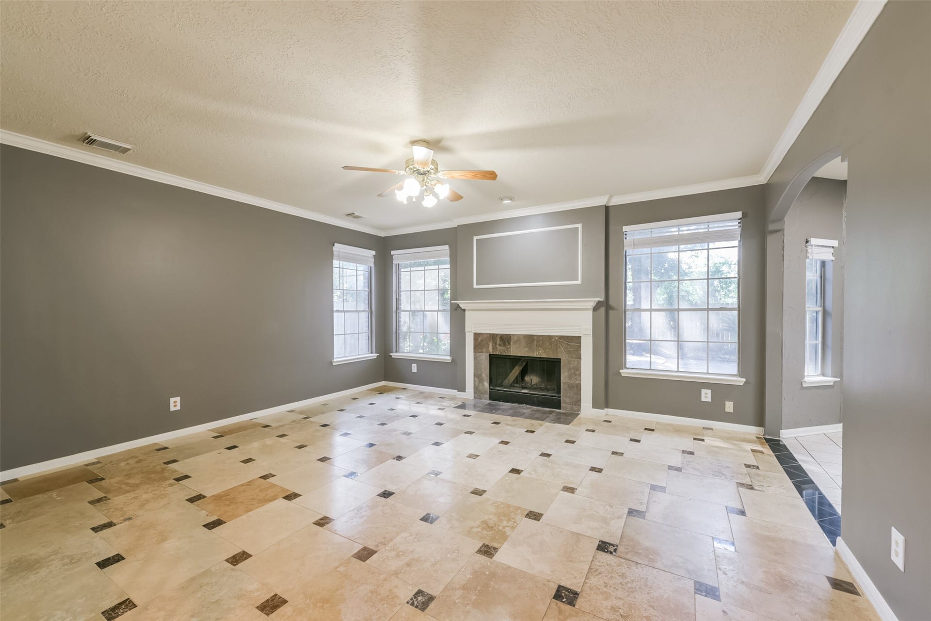 2509 S Mission Circle, Friendswood, TX 77546 Bright and spacious living room featuring elegant tile flooring, a cozy fireplace, and abundant natural light from large windows, perfect for entertaining or relaxing.