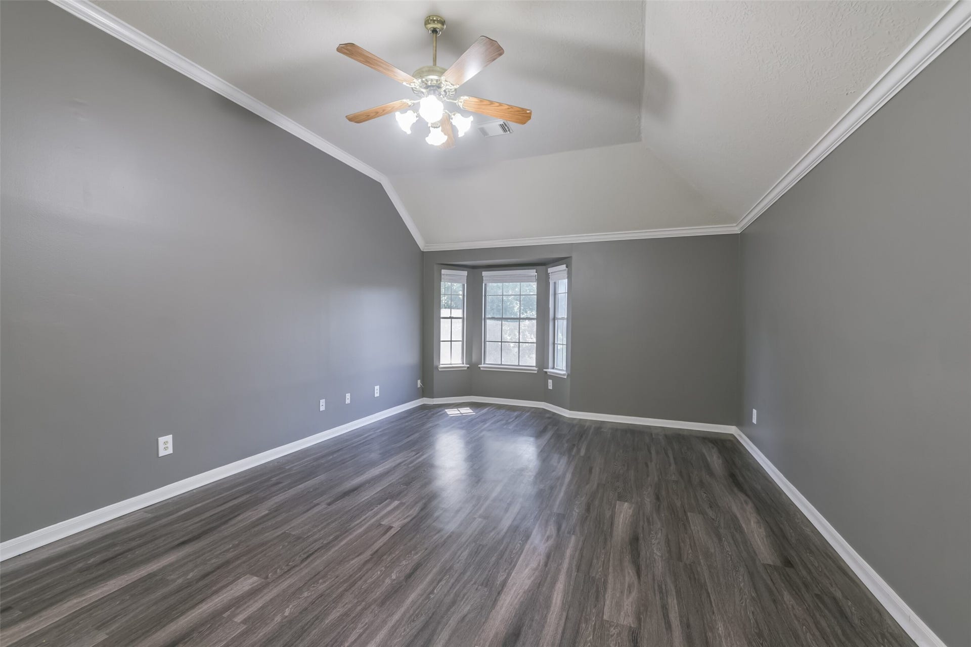 2509 S Mission Circle, Friendswood, TX 77546 Experience tranquility in the upstairs primary bedroom, featuring elegant vaulted ceilings, abundant natural light from the bay window, and rich wood flooring.
