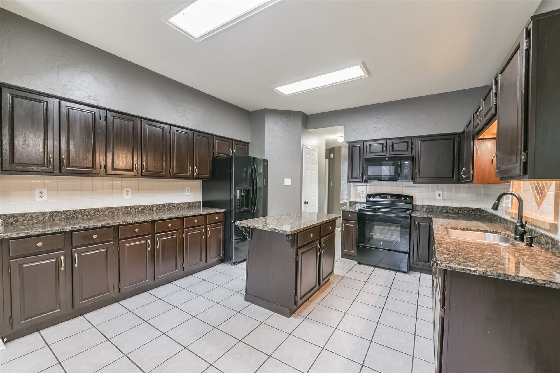 2509 S Mission Circle, Friendswood, TX 77546 Spacious kitchen with sleek dark cabinetry, electric range, and elegant granite countertops, perfect for culinary creativity.