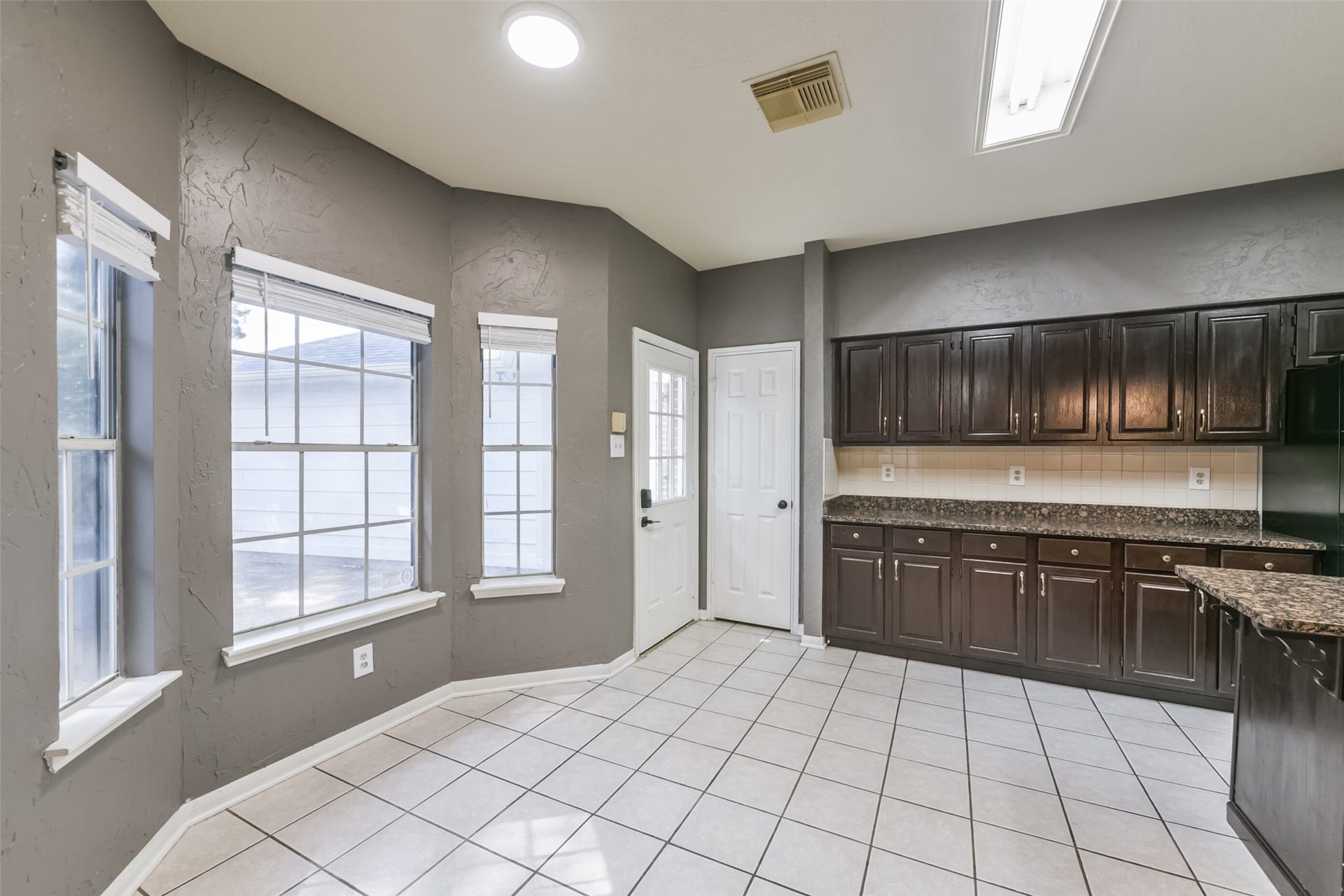 2509 S Mission Circle, Friendswood, TX 77546 Bright and inviting, this kitchen features ample natural light through large windows, complementing the rich cabinetry and spacious tiled floorsperfect for morning gatherings.