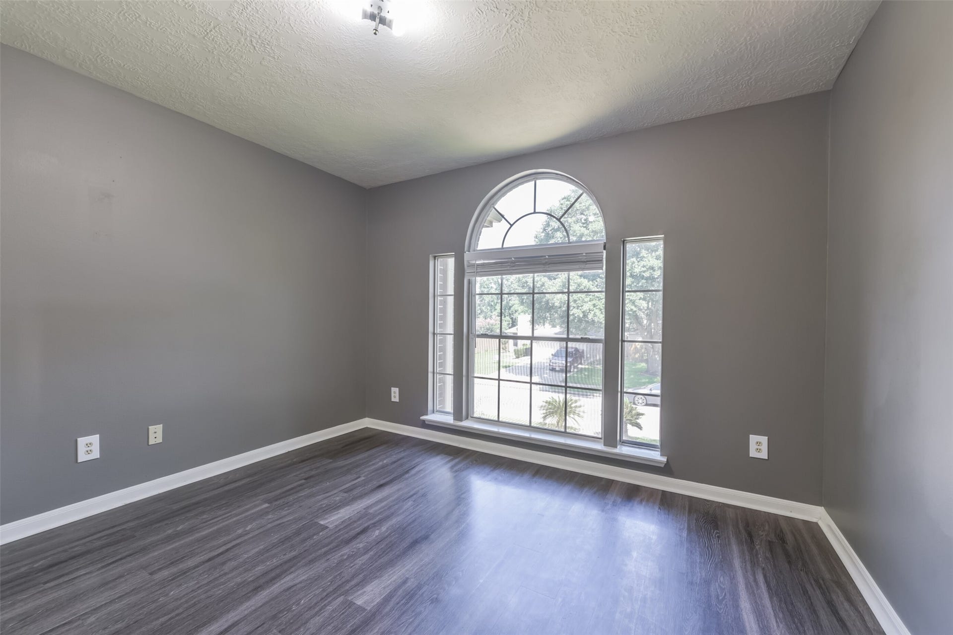 2509 S Mission Circle, Friendswood, TX 77546 Bright and inviting, this secondary bedroom features elegant flooring and a large arched window that fills the space with natural light and offers picturesque views.