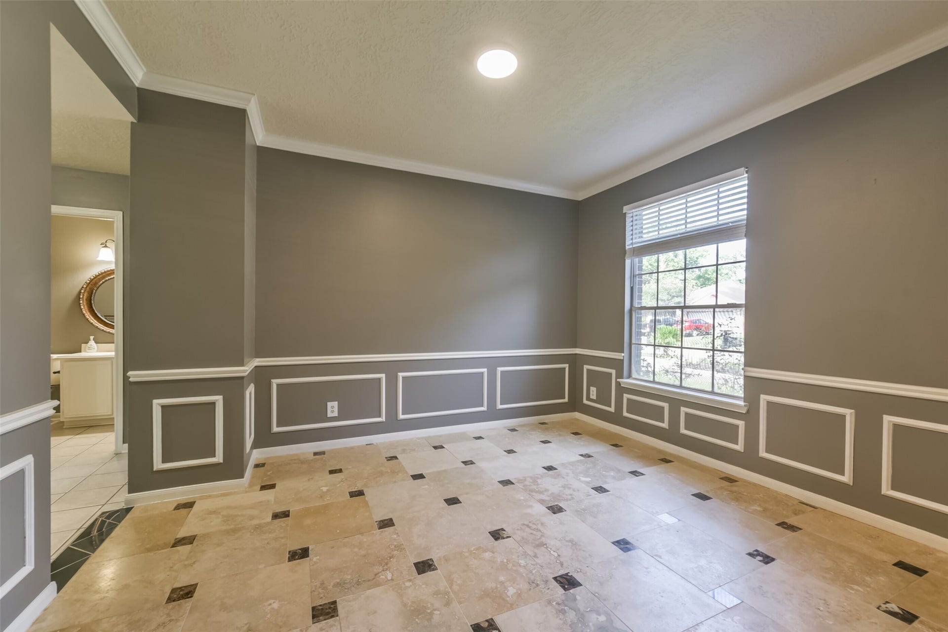2509 S Mission Circle, Friendswood, TX 77546 Elegant dining room featuring classic wainscoting, sophisticated gray walls, and a large window that invites natural light, creating a perfect setting for memorable gatherings.