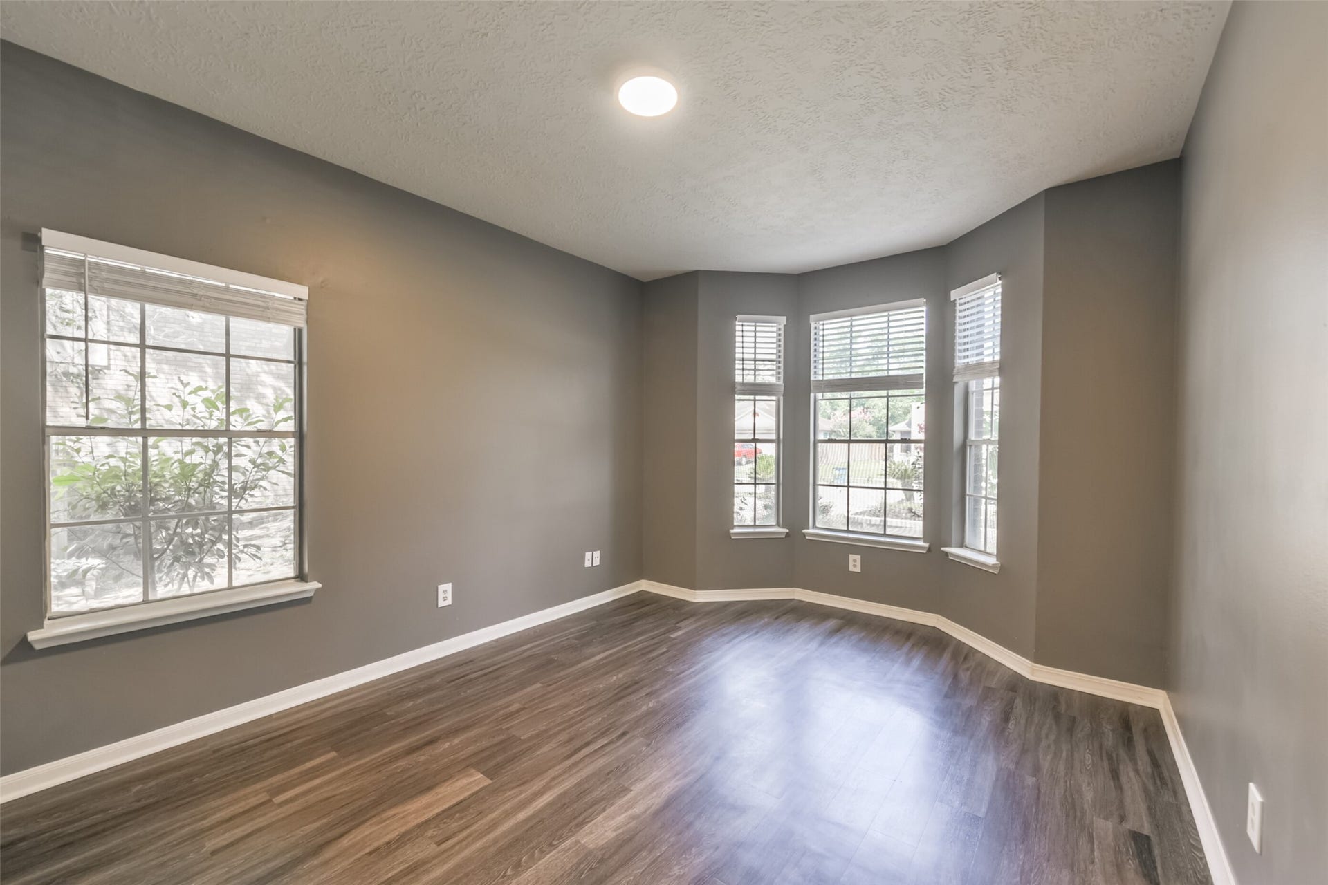 2509 S Mission Circle, Friendswood, TX 77546 Bright and inviting, the downstairs guest room features elegant wood flooring and abundant natural light through charming bay windows, creating the perfect retreat for visitors.