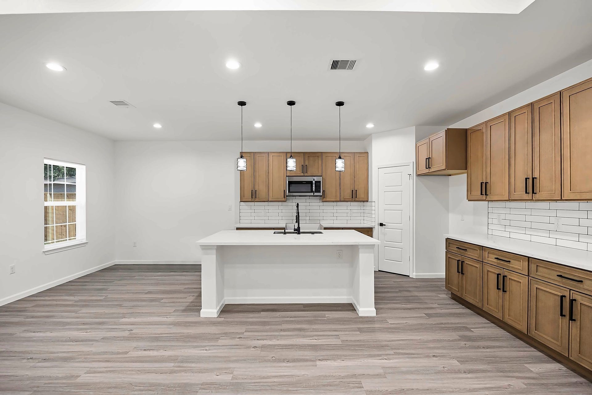 10426 Royal Oaks Drive, Houston, TX 77016 Modern kitchen with sleek cabinetry, a spacious island with pendant lighting, and stylish white subway tile backsplash.