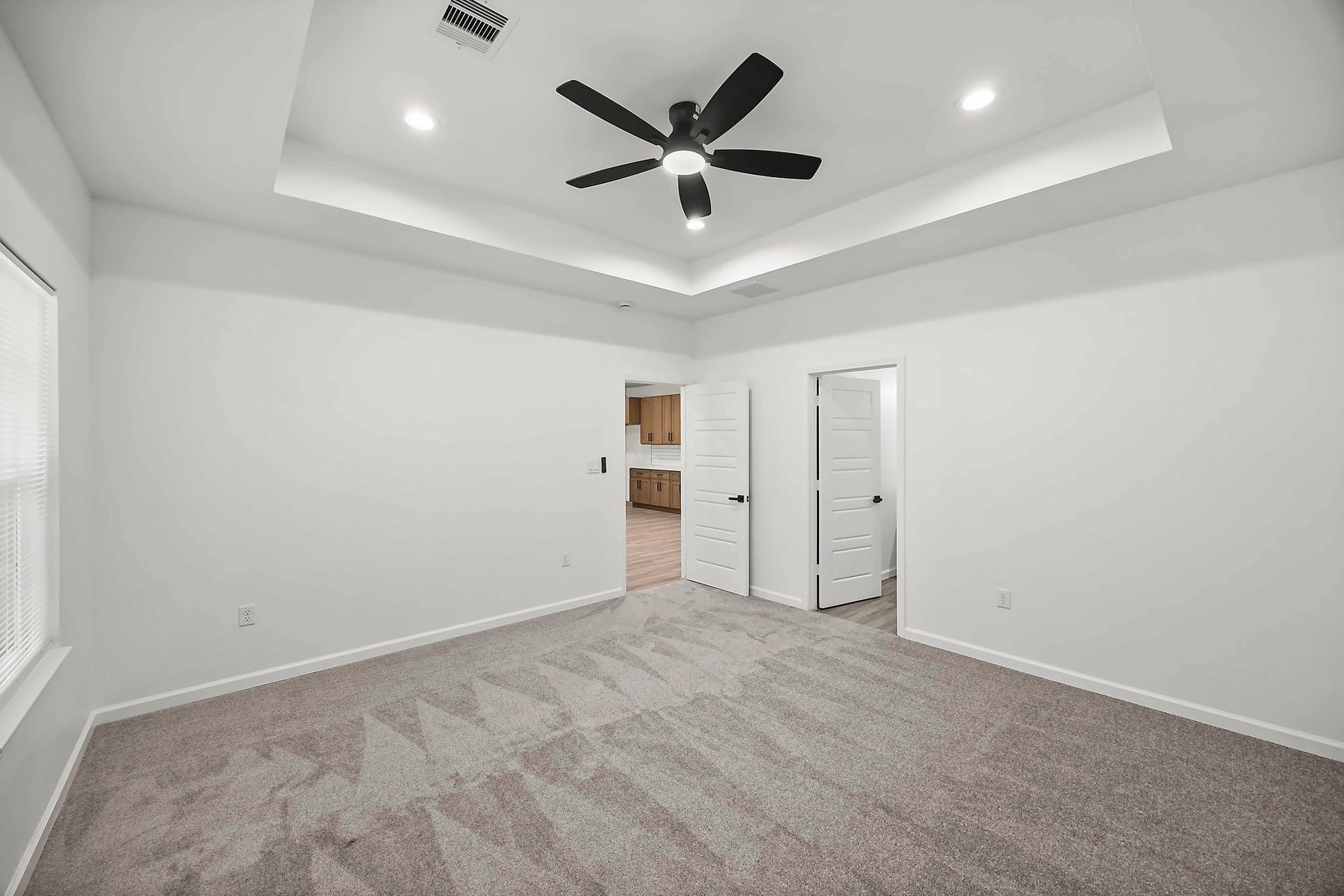 10426 Royal Oaks Drive, Houston, TX 77016 Spacious bedroom with plush carpeting, a modern ceiling fan, and elegant tray ceiling.