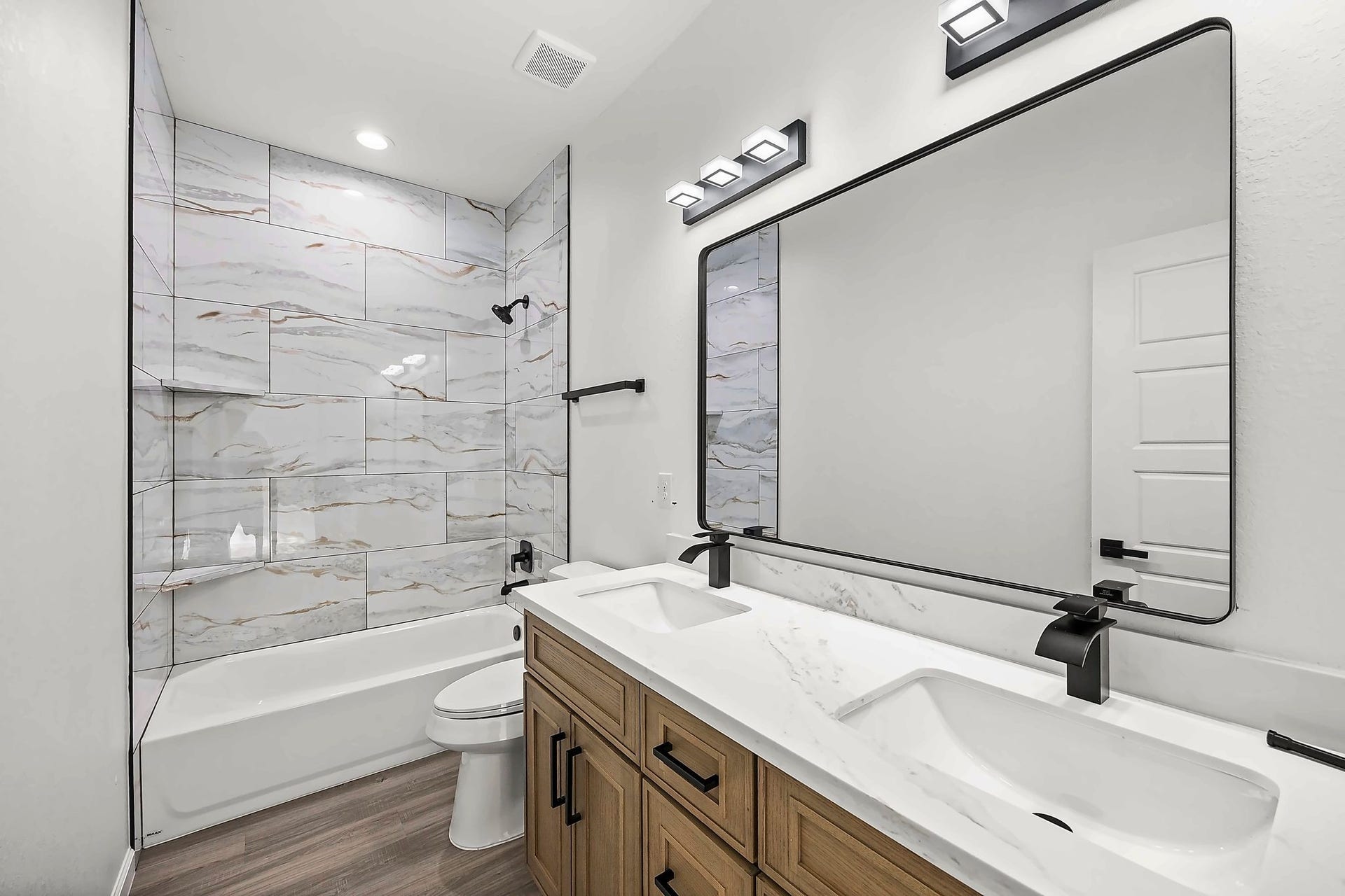 10426 Royal Oaks Drive, Houston, TX 77016 Elegant bathroom featuring a double vanity with a sleek quartz countertop, modern fixtures, and a spacious tub with a stylish tile surround.