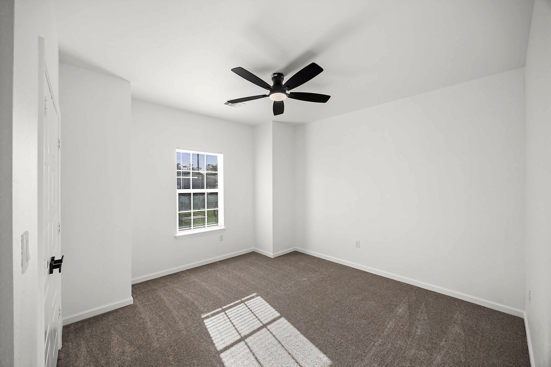 10426 Royal Oaks Drive, Houston, TX 77016 Bright and airy bedroom featuring a large window, plush carpeting, and a sleek ceiling fan for comfort.