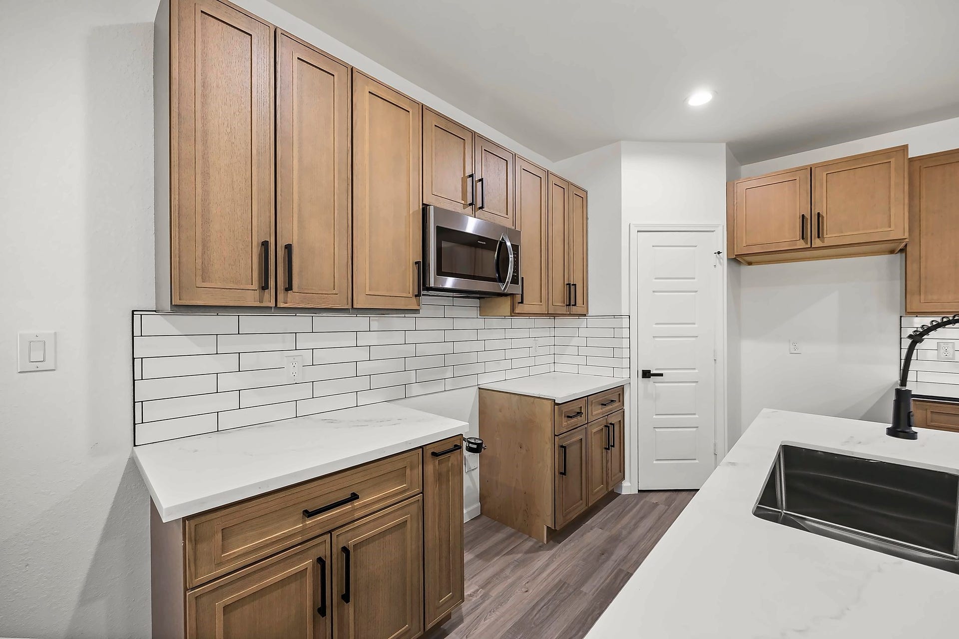 10426 Royal Oaks Drive, Houston, TX 77016 Sleek kitchen featuring modern wood cabinetry, stainless steel appliances, and elegant white countertops with a subway tile backsplash.