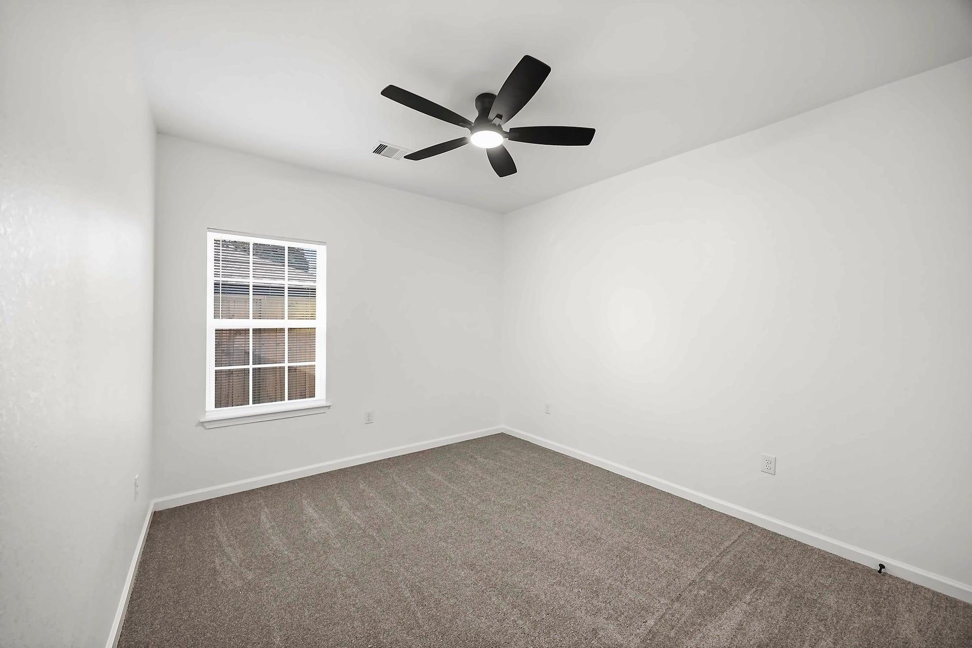 10426 Royal Oaks Drive, Houston, TX 77016 Bright and spacious room featuring fresh carpeting, a modern ceiling fan, and ample natural light from a large window.