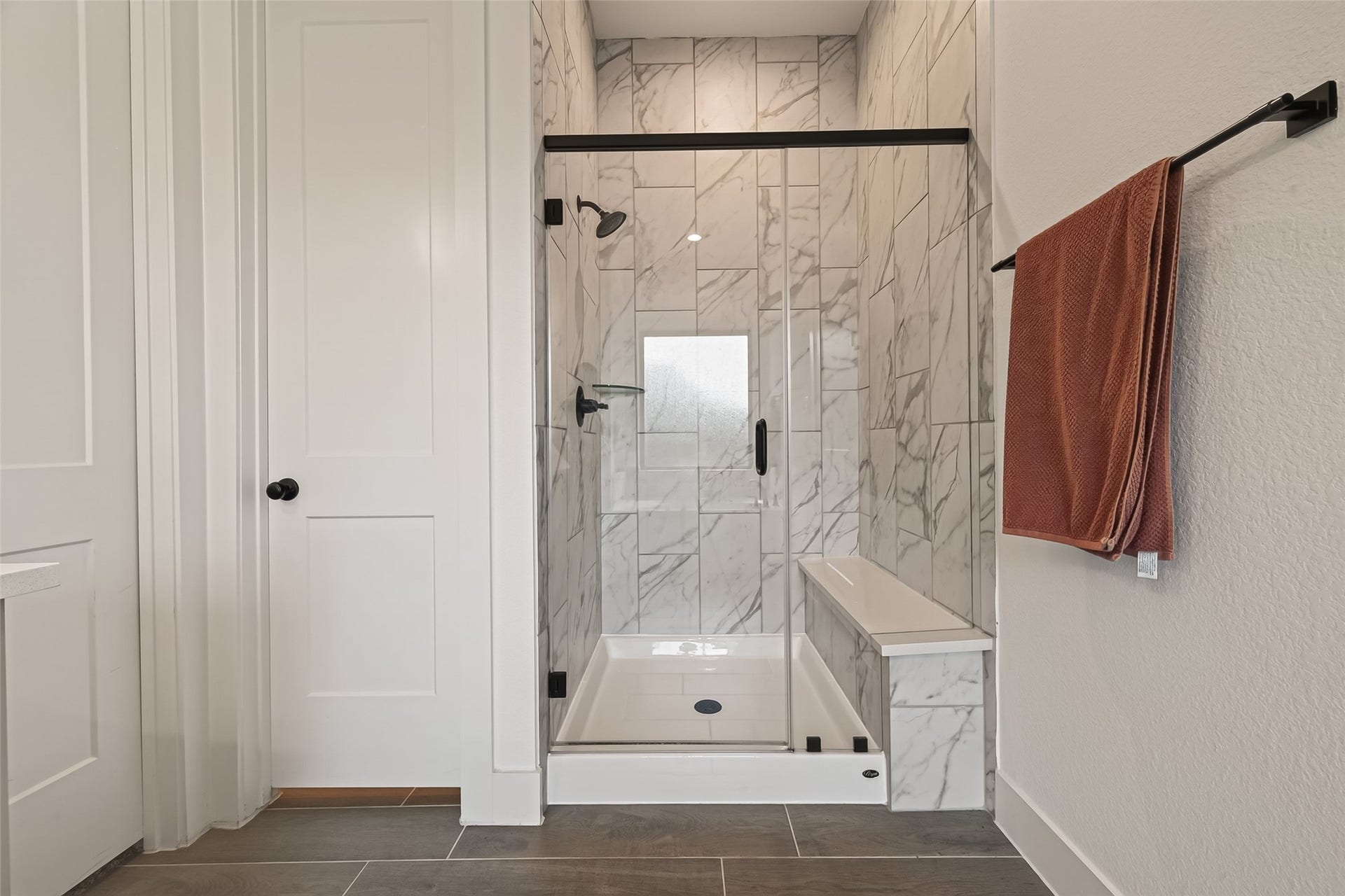 10730 Hidden Rock Drive, Missouri City, TX 77459 Spacious walk-in glass shower featuring floor-to-ceiling tile, a built-in bench, and sleek modern hardware.