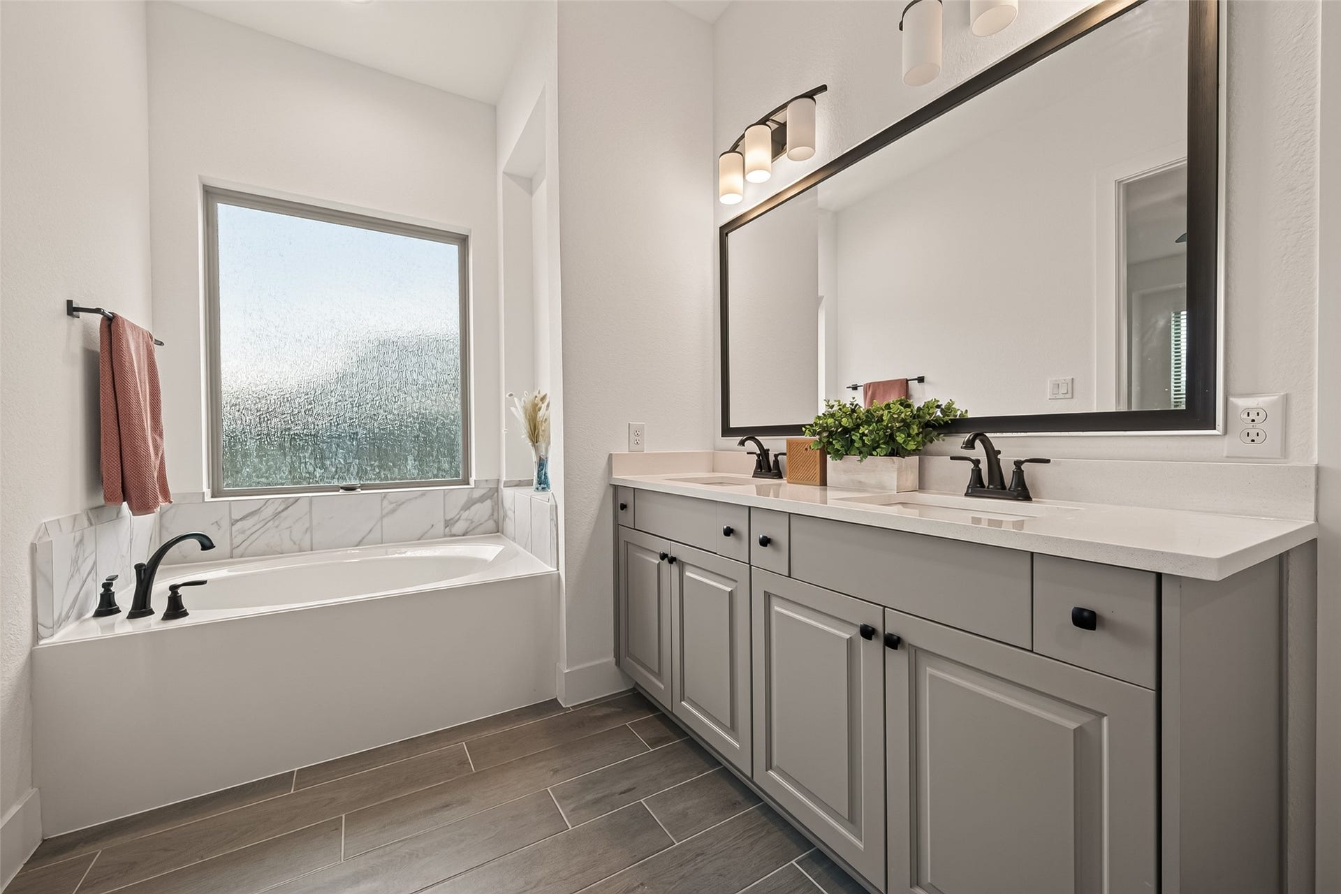 10730 Hidden Rock Drive, Missouri City, TX 77459 Spacious primary bathroom featuring a deep soaking tub positioned elegantly beneath a frosted glass window, which invites an abundance of natural light while ensuring complete privacy.