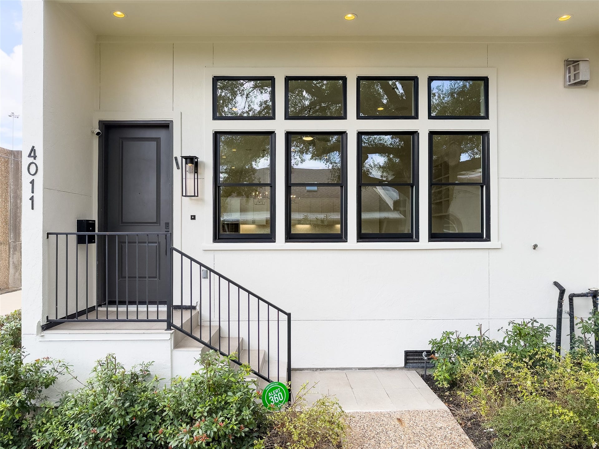 neutral-color tiled stairs to wide, covered front porch outside front door; striking black framed windows