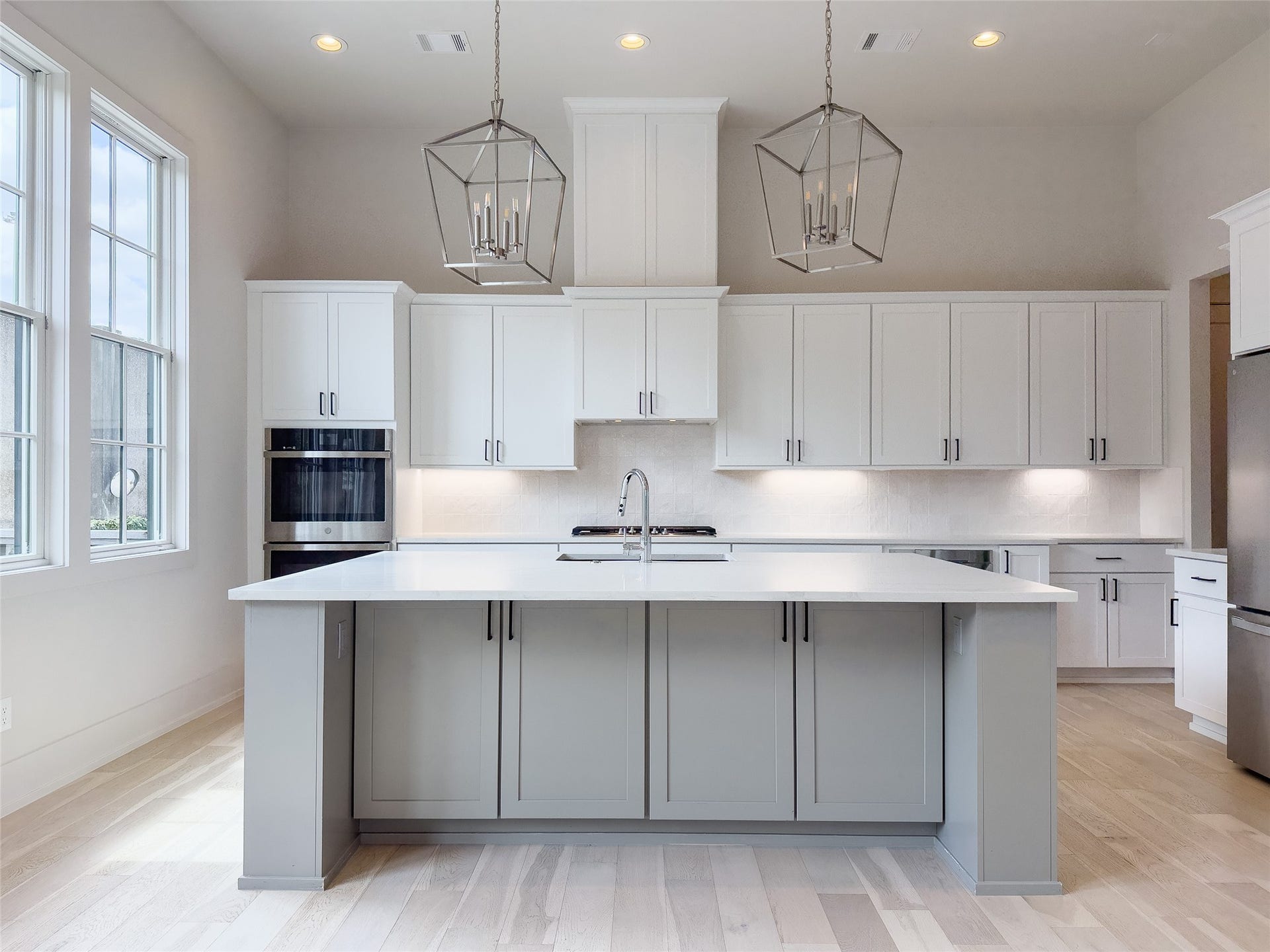 pendant lights over expansive kitchen eat-in island w/room for bar stools, abundant Shaker cabinetry