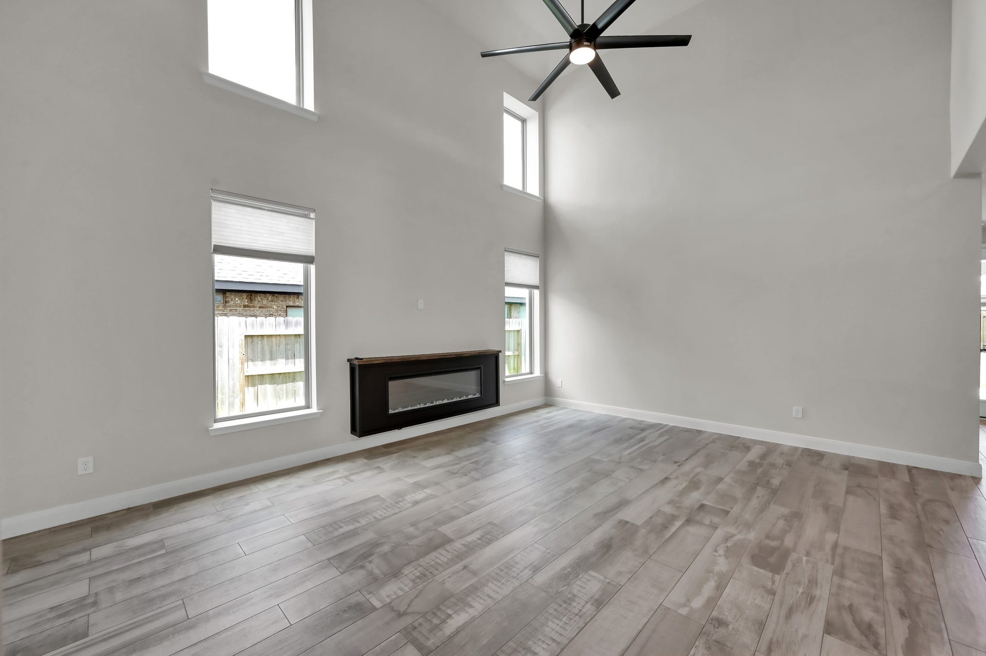 550 Chestnut Reef Court, Conroe, TX 77304 Light-filled living room with soaring ceilings, tall windows, and a sleek electric fireplace.