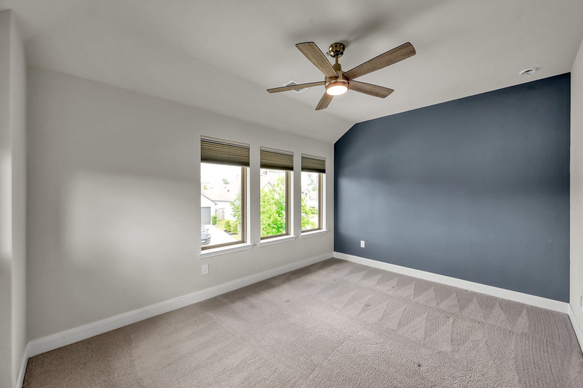 550 Chestnut Reef Court, Conroe, TX 77304 Bright secondary bedroom with clean carpeting, modern ceiling fan, and a stylish accent wall.