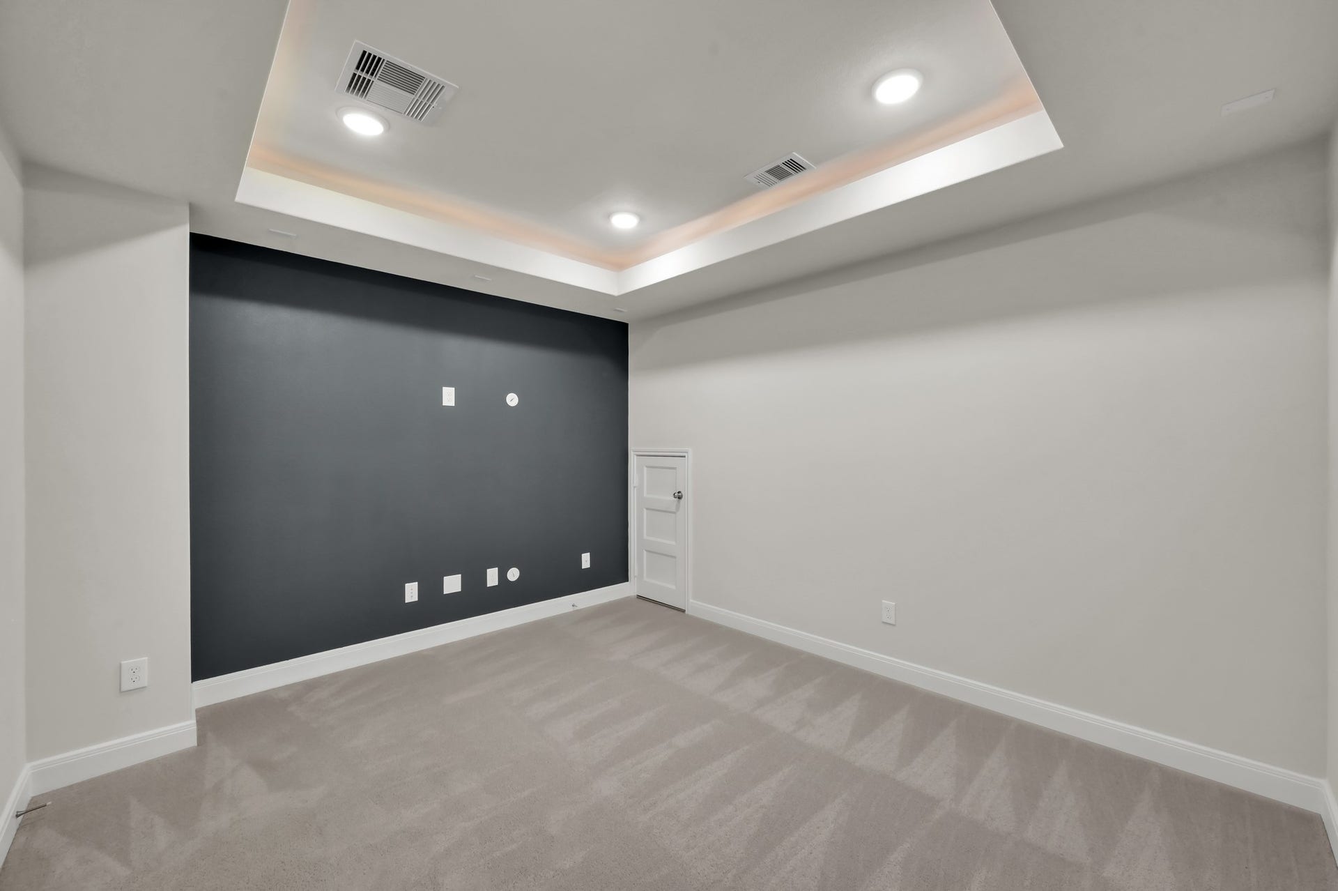 550 Chestnut Reef Court, Conroe, TX 77304 Cozy media room with tray ceiling, recessed lighting, and a bold accent wall ready for entertainment setup.
