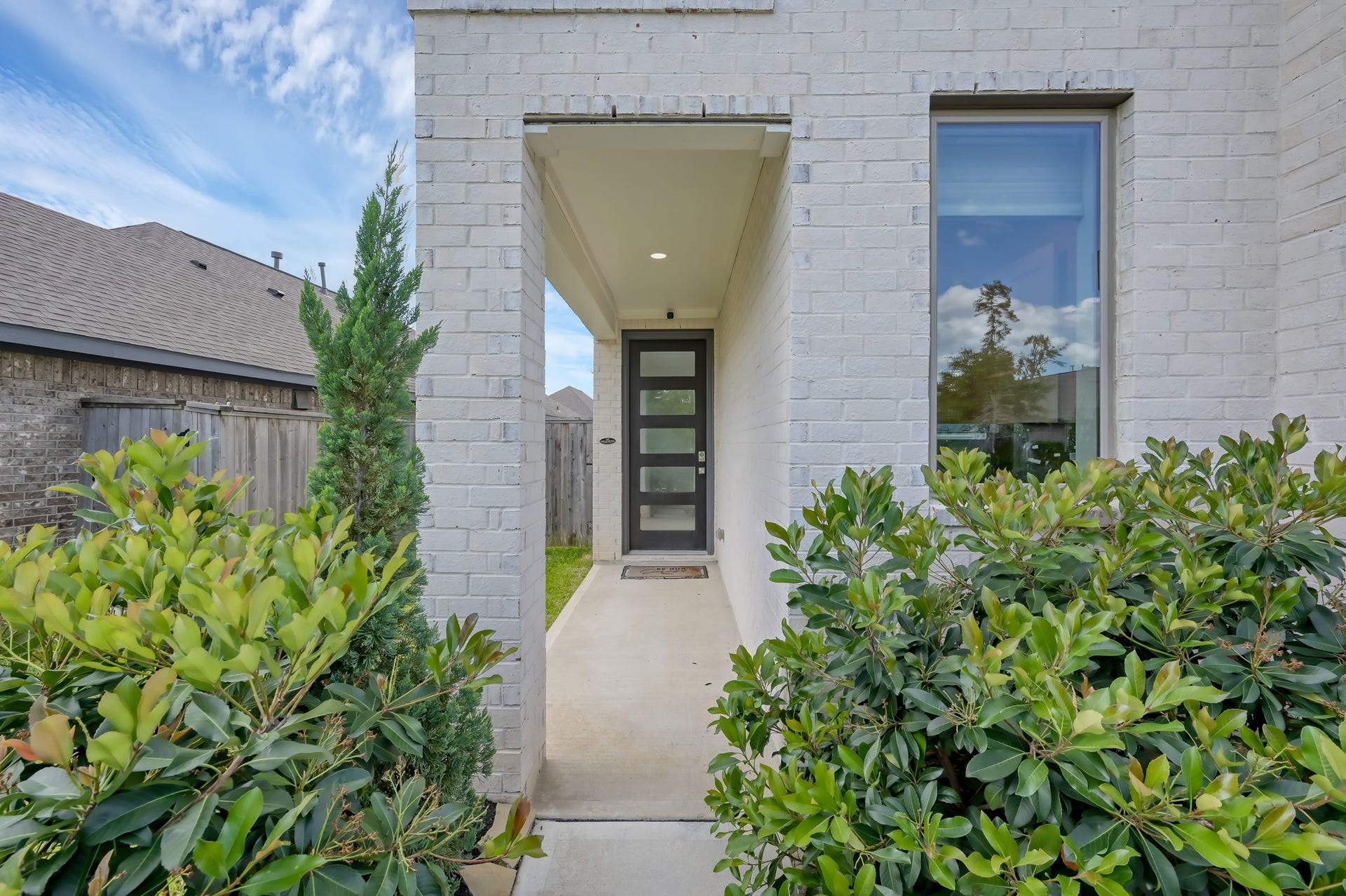 550 Chestnut Reef Court, Conroe, TX 77304 Inviting covered entry with modern front door and lush landscaping for added privacy.