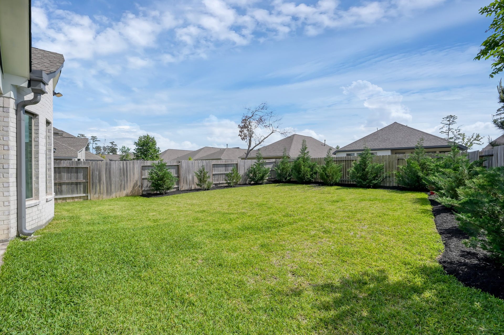 550 Chestnut Reef Court, Conroe, TX 77304 Spacious, fully fenced backyard with lush green lawn, fresh landscaping, and plenty of room for entertaining or outdoor additions.