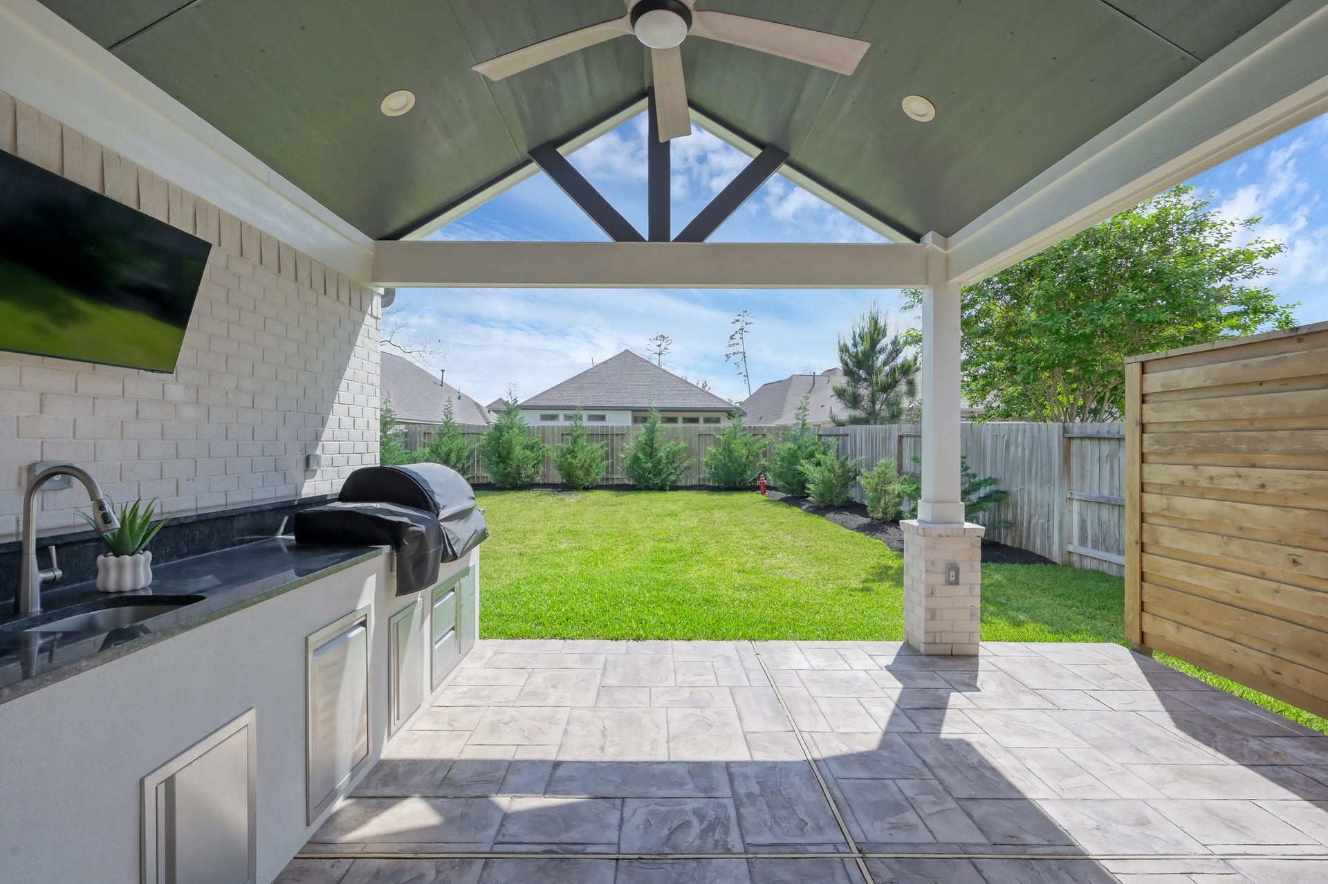 550 Chestnut Reef Court, Conroe, TX 77304 Spacious covered patio with outdoor kitchen, ceiling fan, and TV setupperfect for entertaining while enjoying the private backyard.