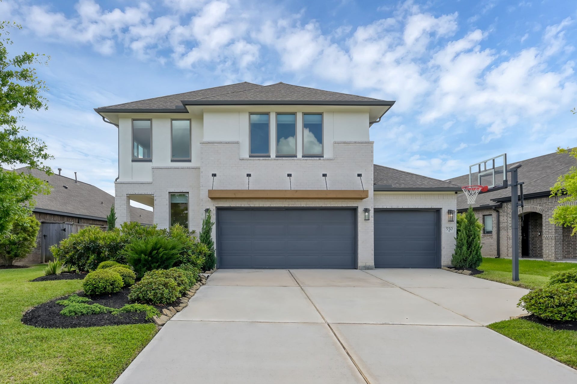 550 Chestnut Reef Court, Conroe, TX 77304 Modern two-story home with clean white brick elevation, 3-car garage, and well-manicured landscaping on a quiet cul-de-sac street.