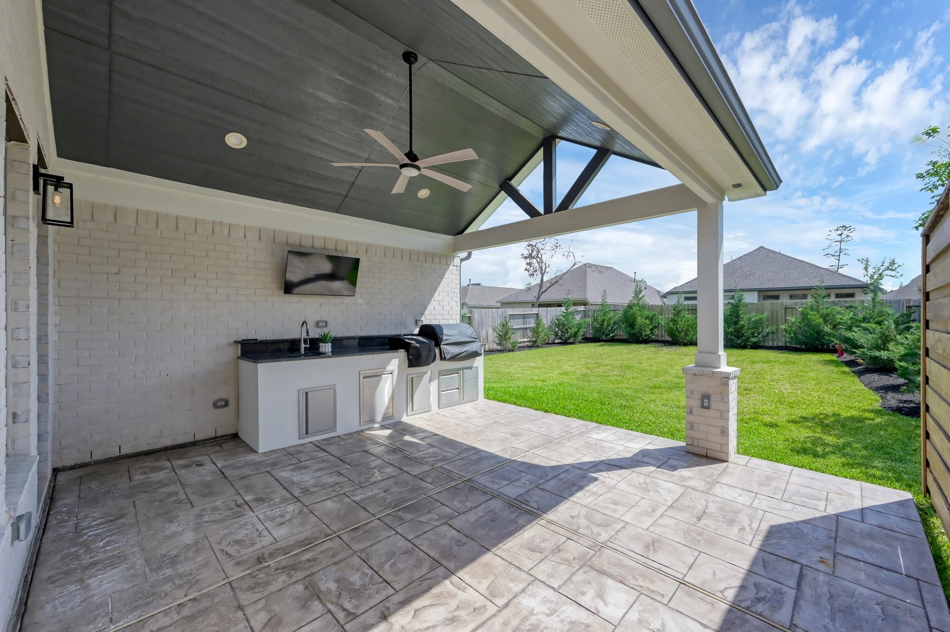 550 Chestnut Reef Court, Conroe, TX 77304 Spacious covered patio with outdoor kitchen, ceiling fan, and TV setupperfect for entertaining while enjoying the private backyard.