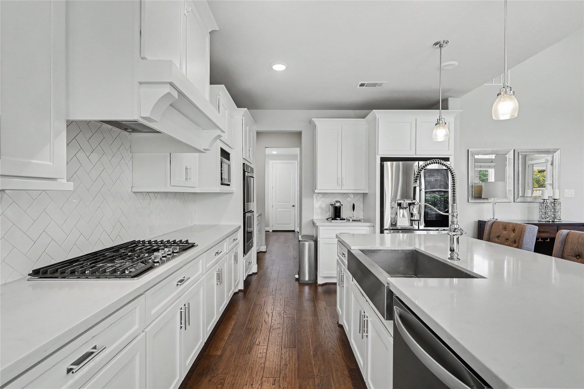 28216 Regal Wood Court, Spring, TX 77386 Kitchen featuring built-in appliances, white cabinetry, and island seating.