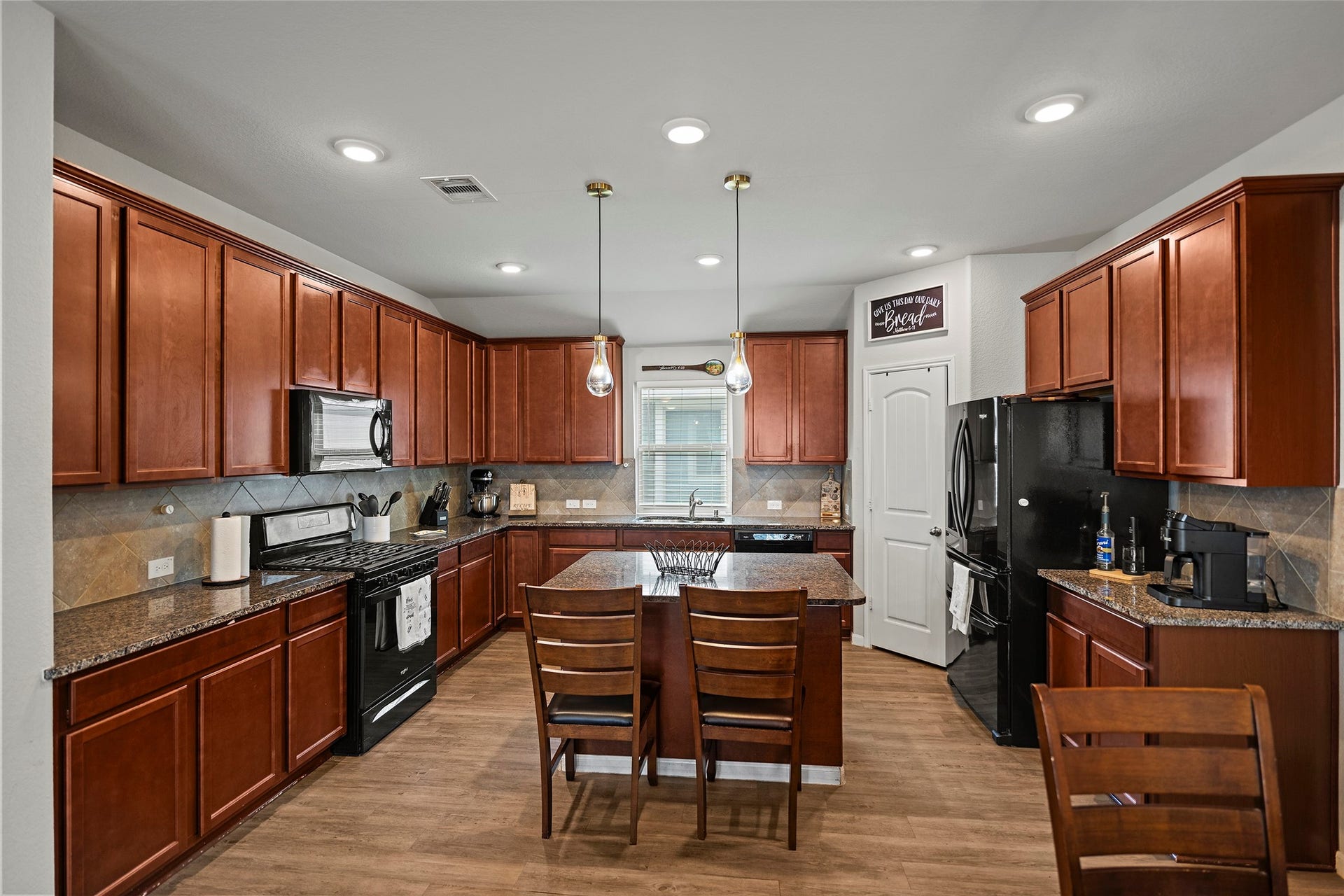 6938 Scarlet Sagebrush Street, Katy, TX 77449 The kitchen features 42" cabinets, granite countertops, a tile backsplash, and black appliances.