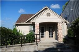6001 Reims Road, #1202, Houston, TX 77036 Charming single-story home with a gabled roof, stone accents, and double French doors. Features a front ramp for easy access and is surrounded by lush greenery, offering a cozy and inviting exterior.