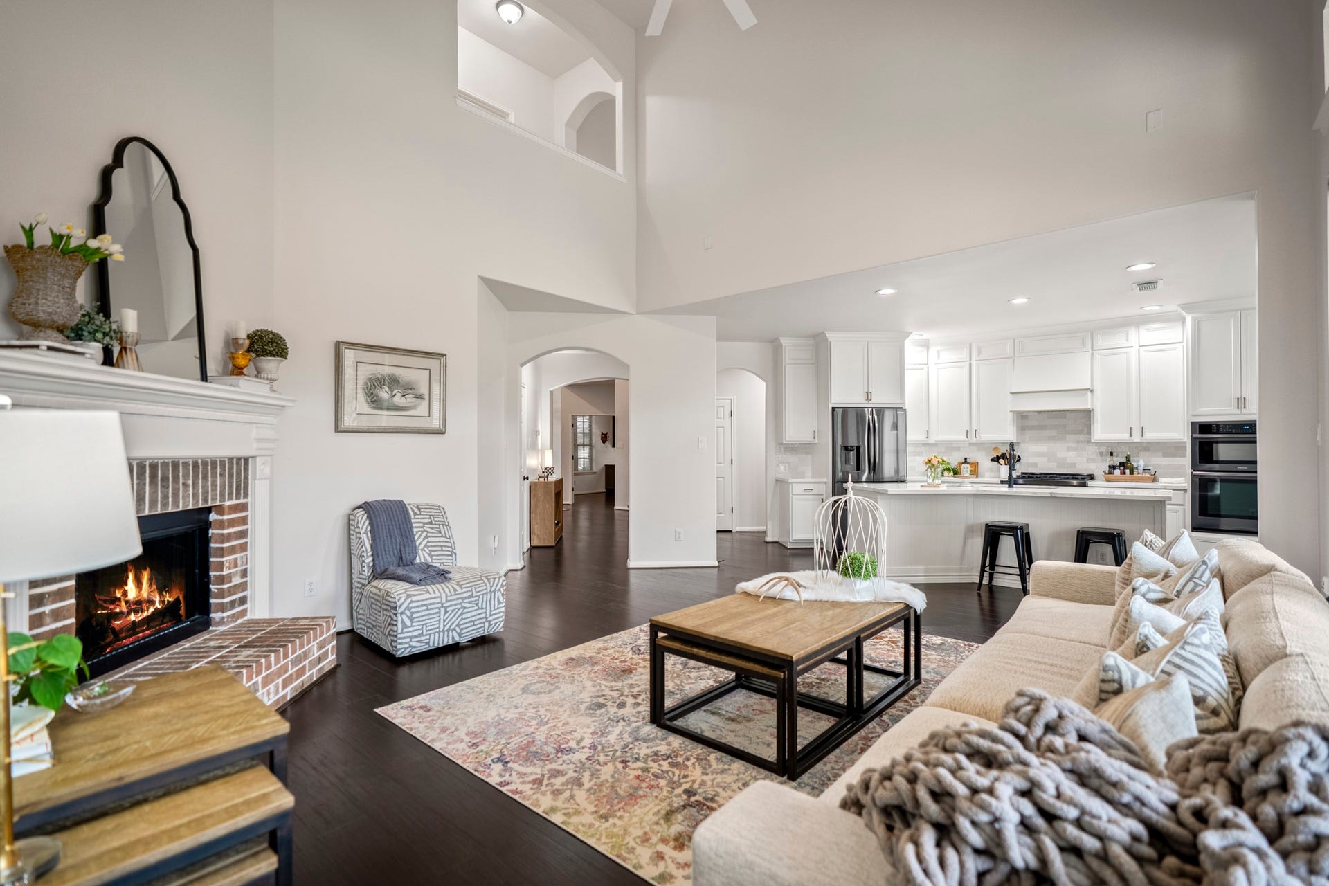 The spacious living area perfectly balances grand architectural scale with a warm, inviting atmosphere around the cozy fireplace. The soaring ceilings and stacked upper transom create an incredibly airy feel.