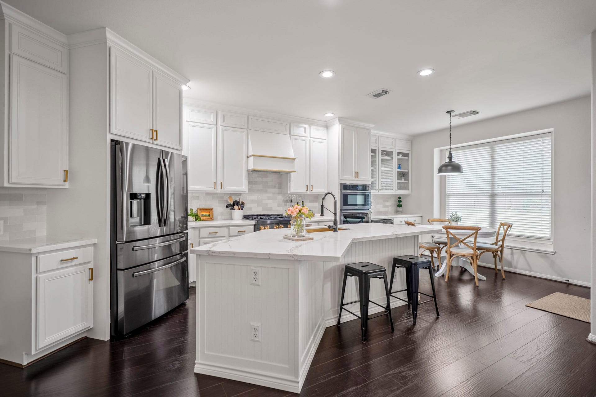 The kitchen is the true heart of the home, a light-filled, gourmet kitchen is a masterpiece featuring an expansive island with a breakfast bar overhang, beautifully wrapped in classic white beadboard and topped with luxurious quartz countertops.