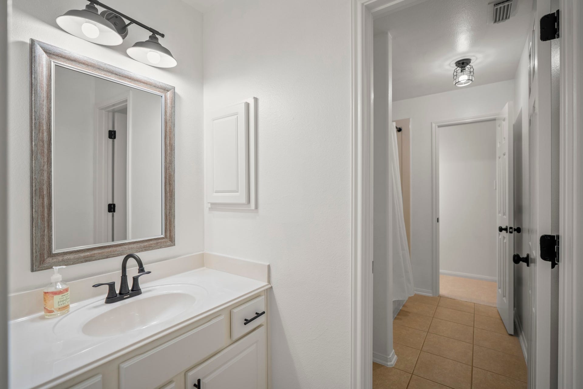 The upstairs shared bathroom has updated lighting, and a nice framed mirror, as well as plenty of storage and a tub / shower combo.