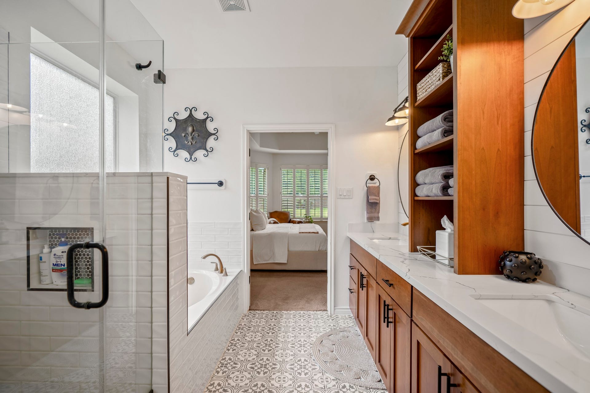 Indulge in a luxurious, spa-like escape with a tiled soaking tub deck, glass enclosed shower and modern intricate patterned floor tile.