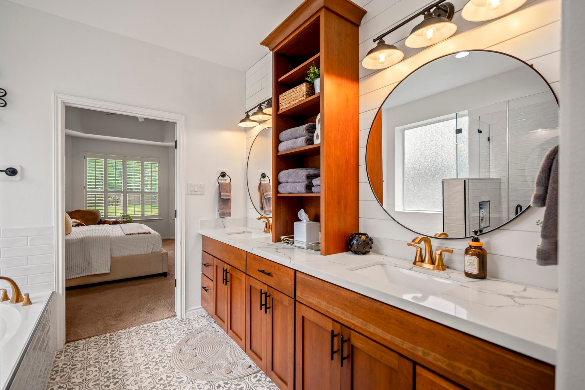 This stunning expansive dual vanity crafted from rich, warm wood cabinetry, beautifully anchored by a custom floor-to-ceiling open shelving tower for ultimate linen storage or display.