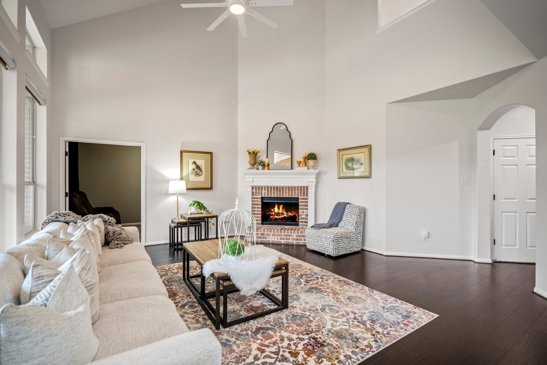 The central focus is a stunning brick-accented fireplace featuring a detailed white mantle, perfect for cozying up on cooler evenings and looking forward to being decorated for the holidays.